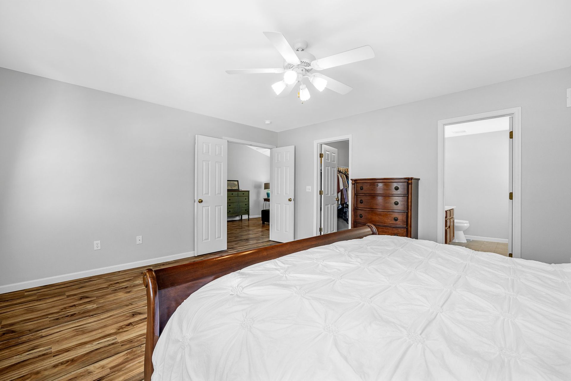 A bedroom with a bed , dresser , and ceiling fan.