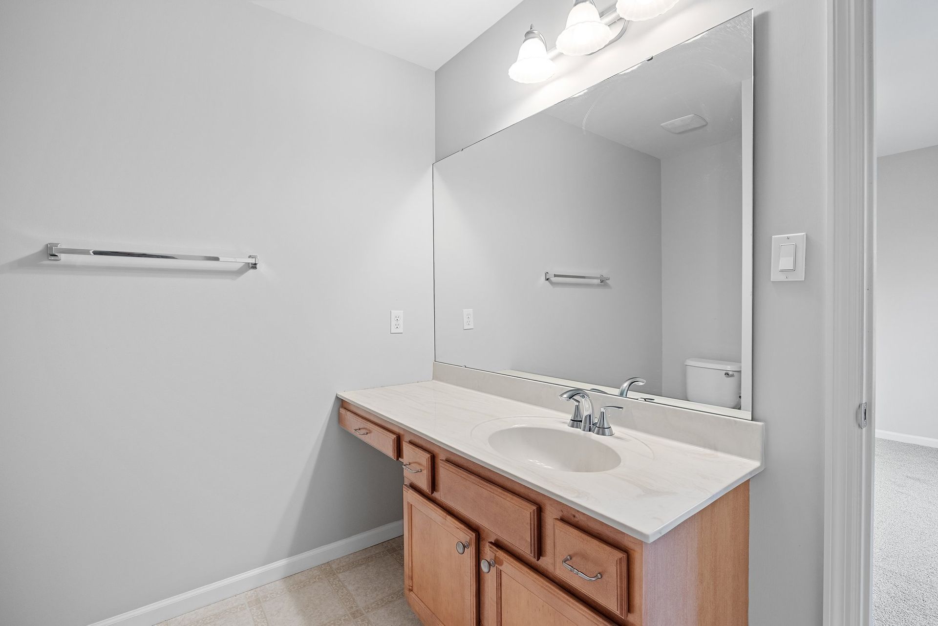 A bathroom with a sink , mirror and towel rack.