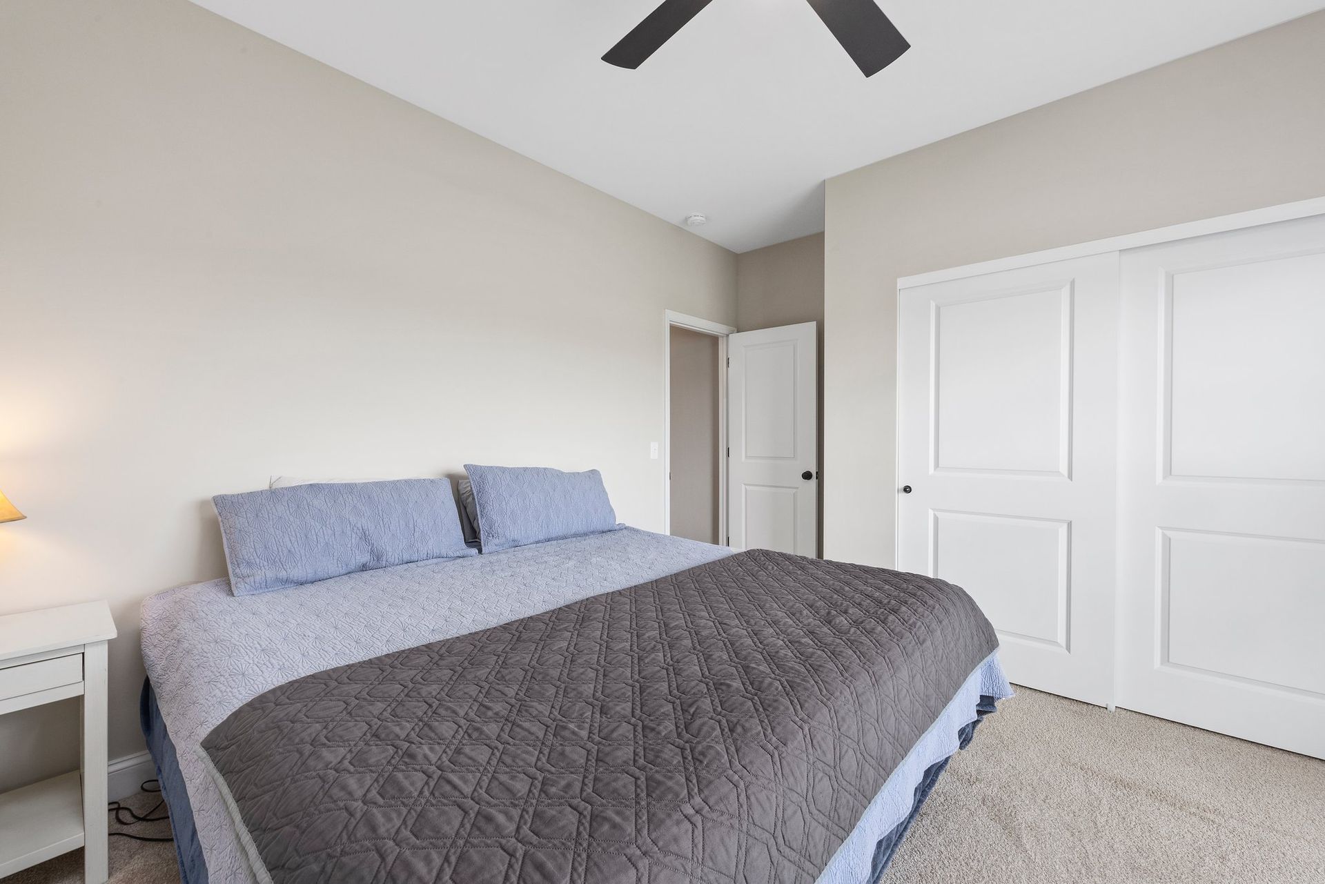 A bedroom with a bed and a ceiling fan.