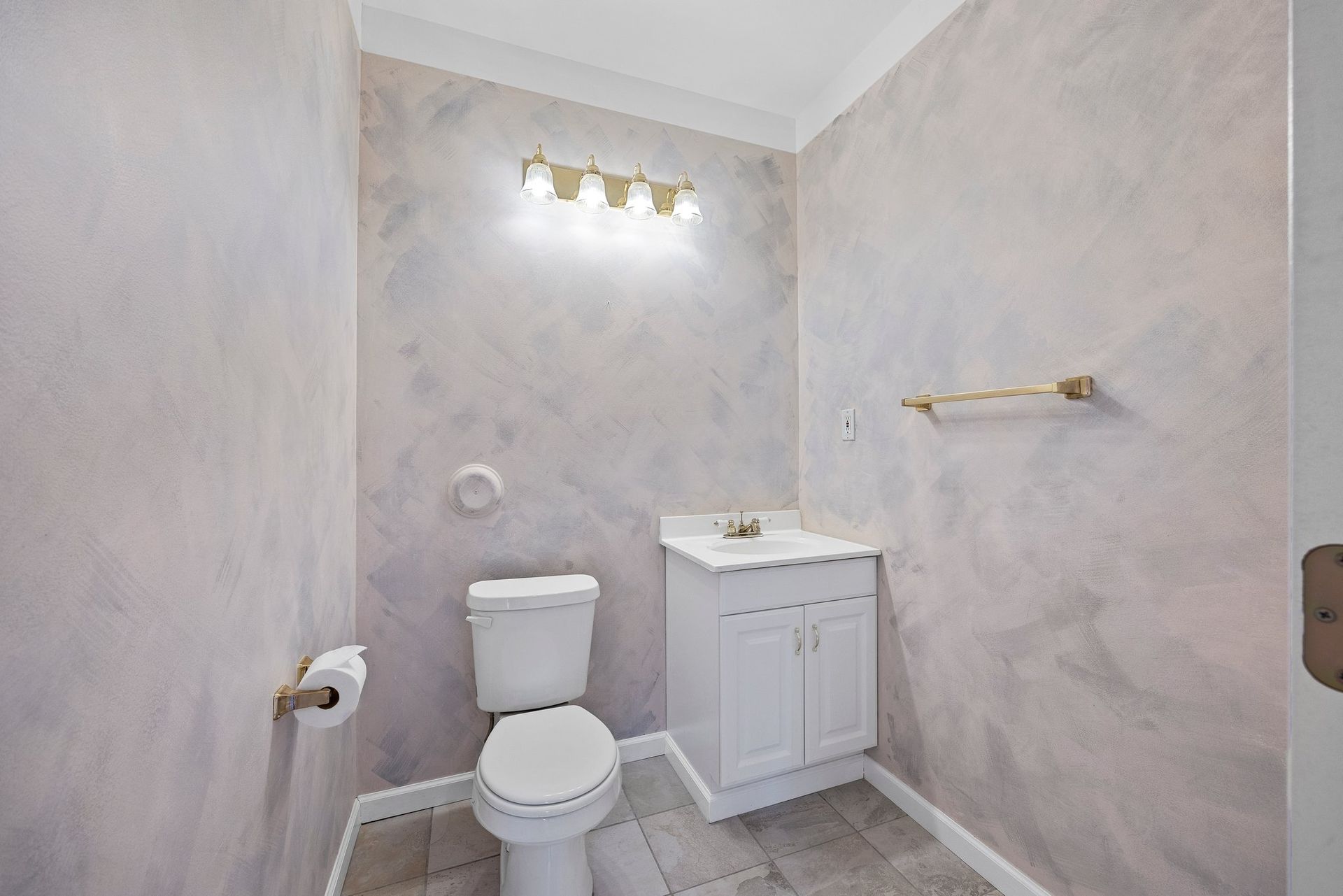 A bathroom with a toilet , sink , and light fixture.