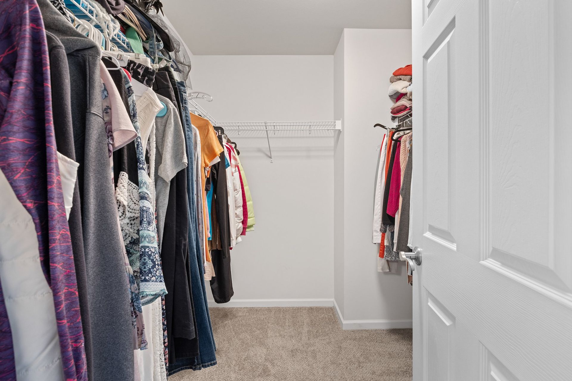 A walk in closet filled with clothes and a door.