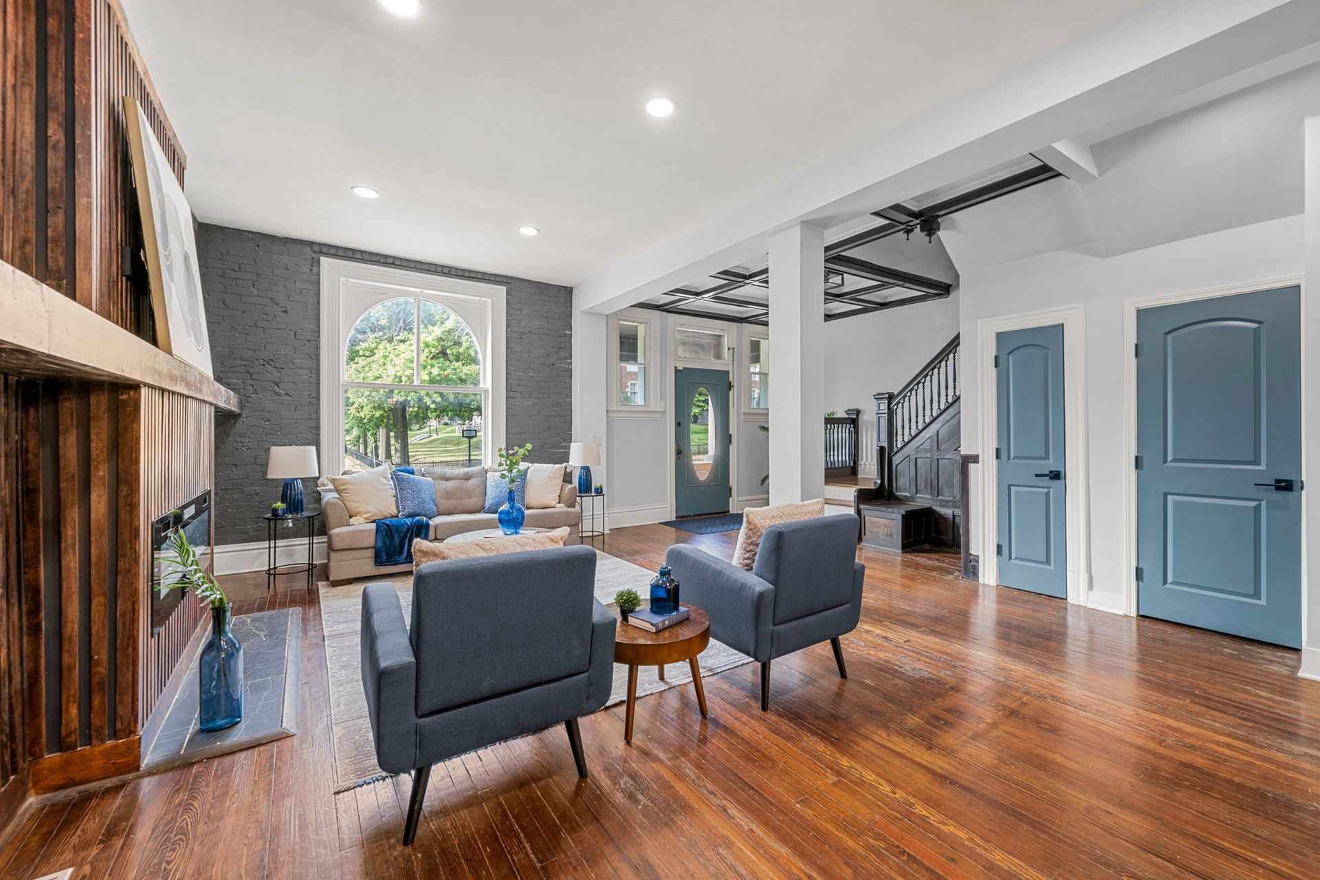 Living room with blue armchairs, hardwood floors, and a view to the front door.