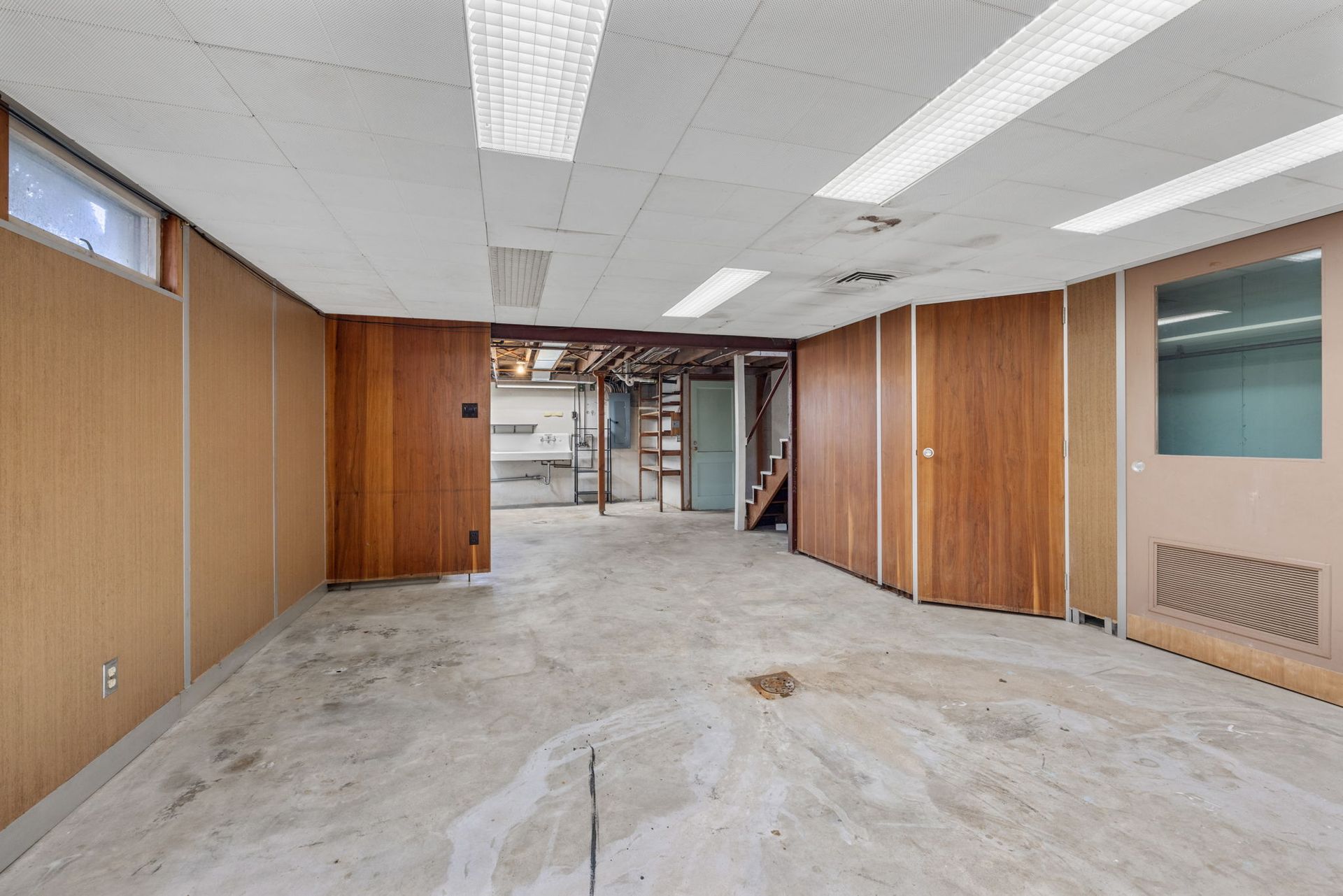 An empty basement with wooden walls and a concrete floor.