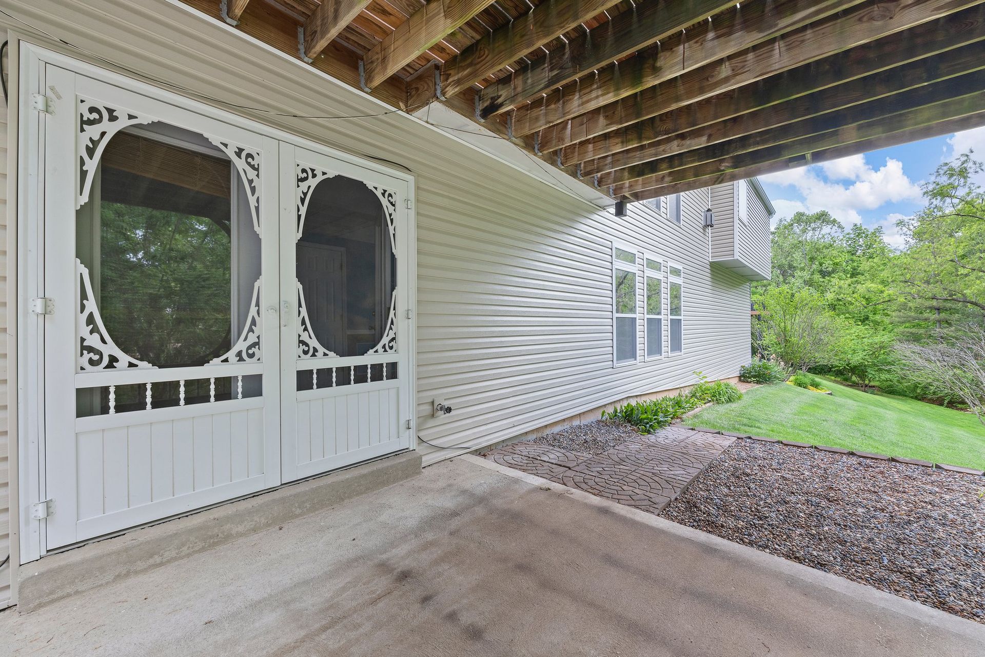 A screened in porch with a white house in the background