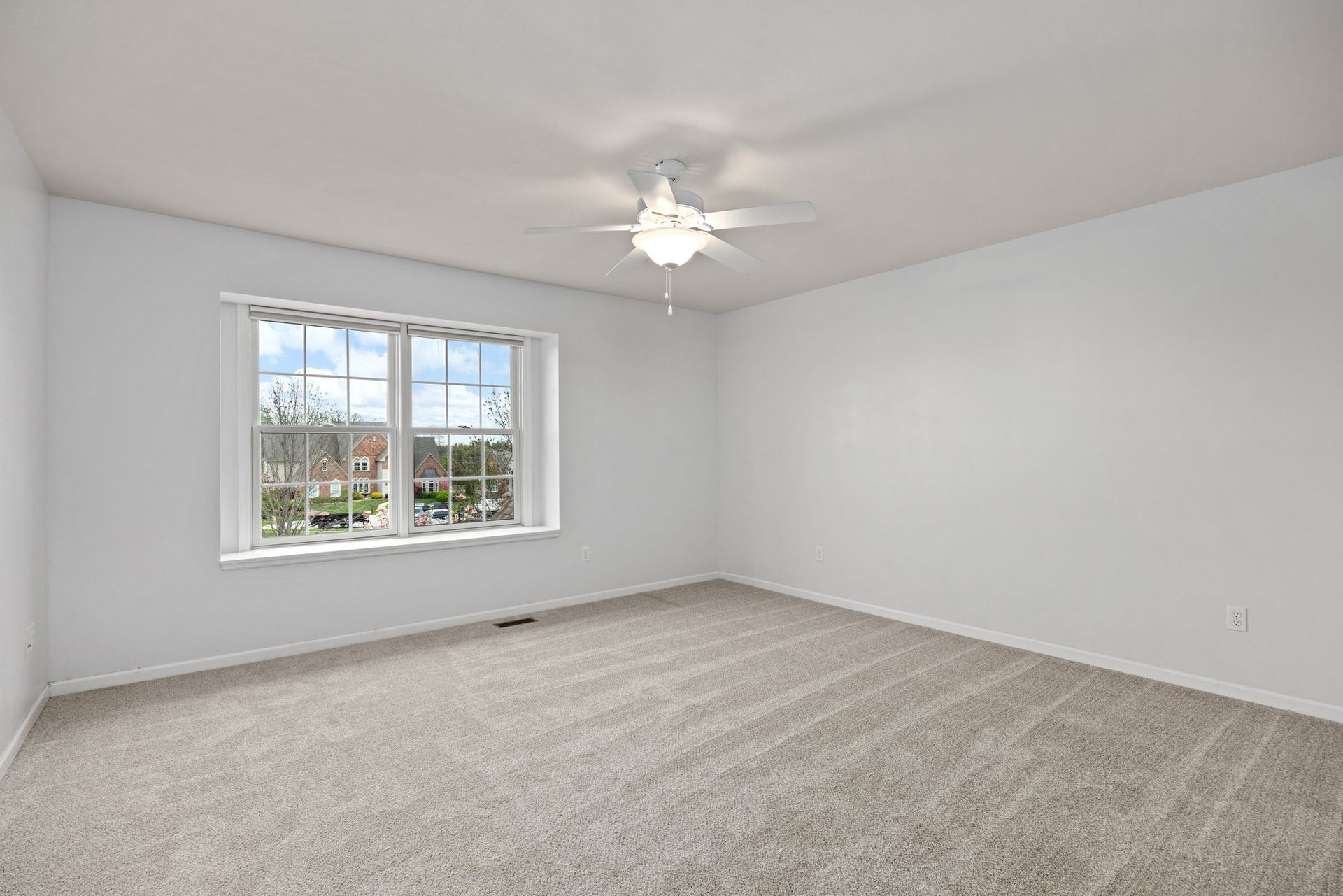 An empty bedroom with a ceiling fan and a window.