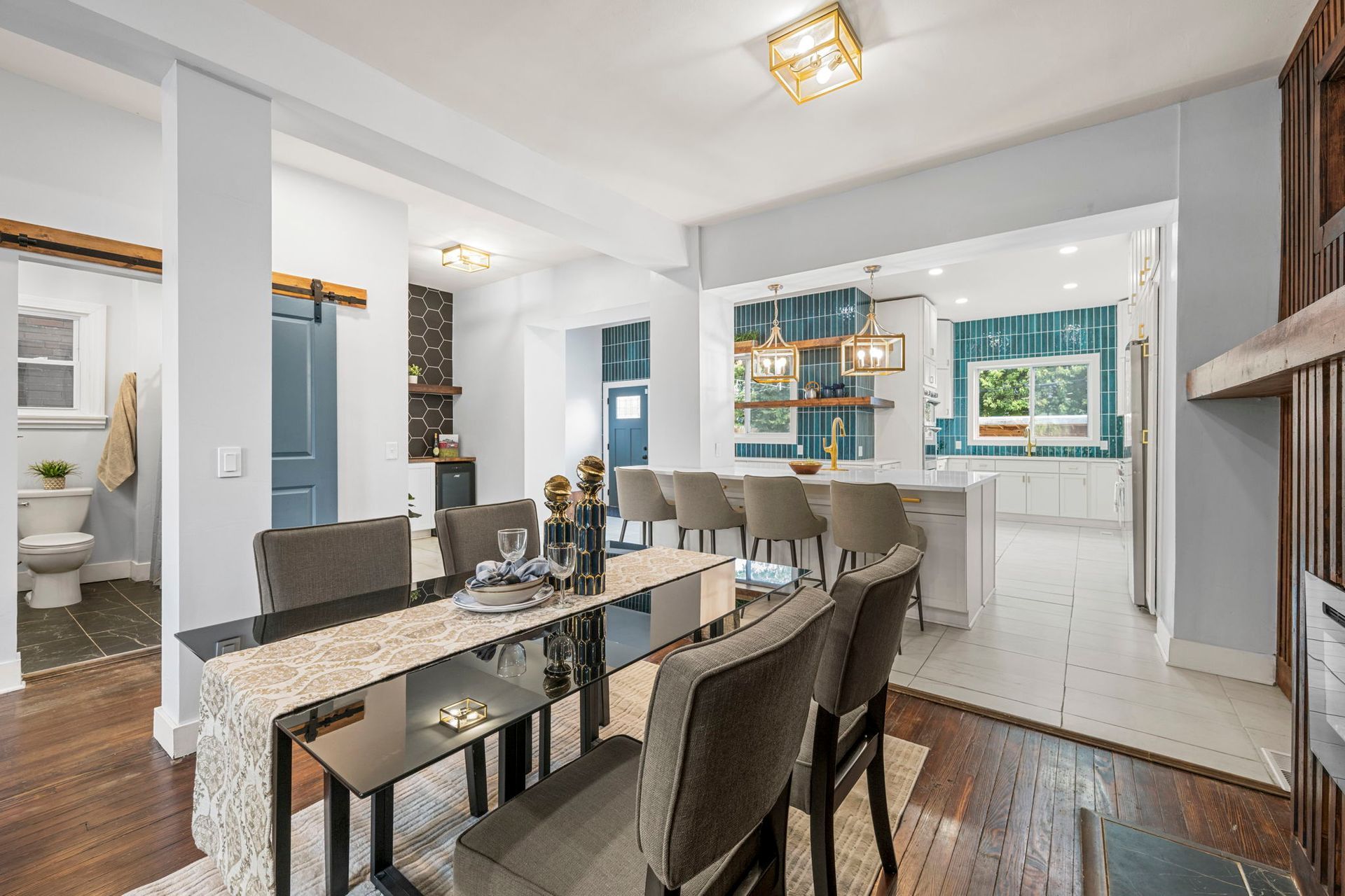 Dining room with table set for guests, open to a modern kitchen.