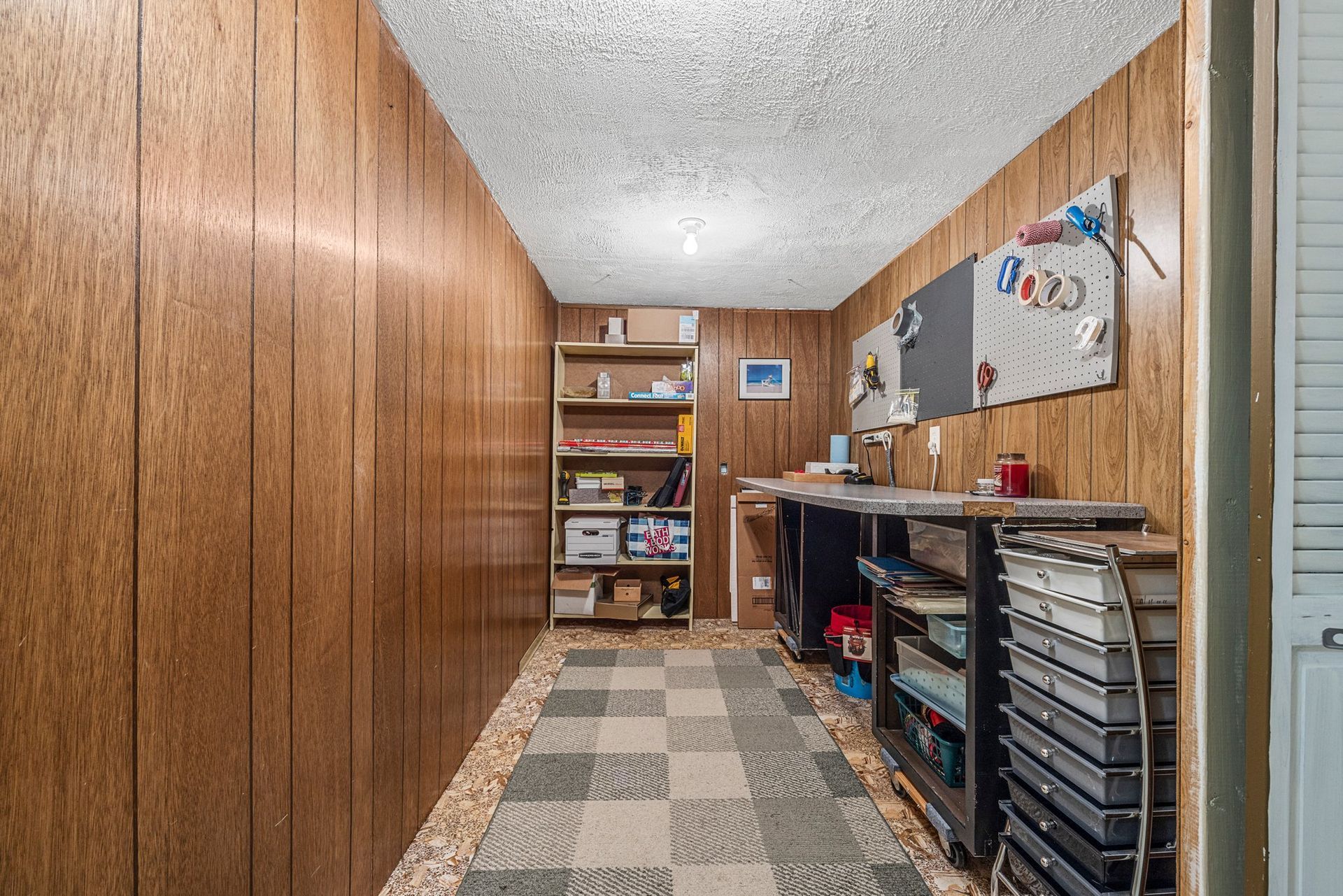 A long hallway with wood paneling and a checkered floor in a basement.