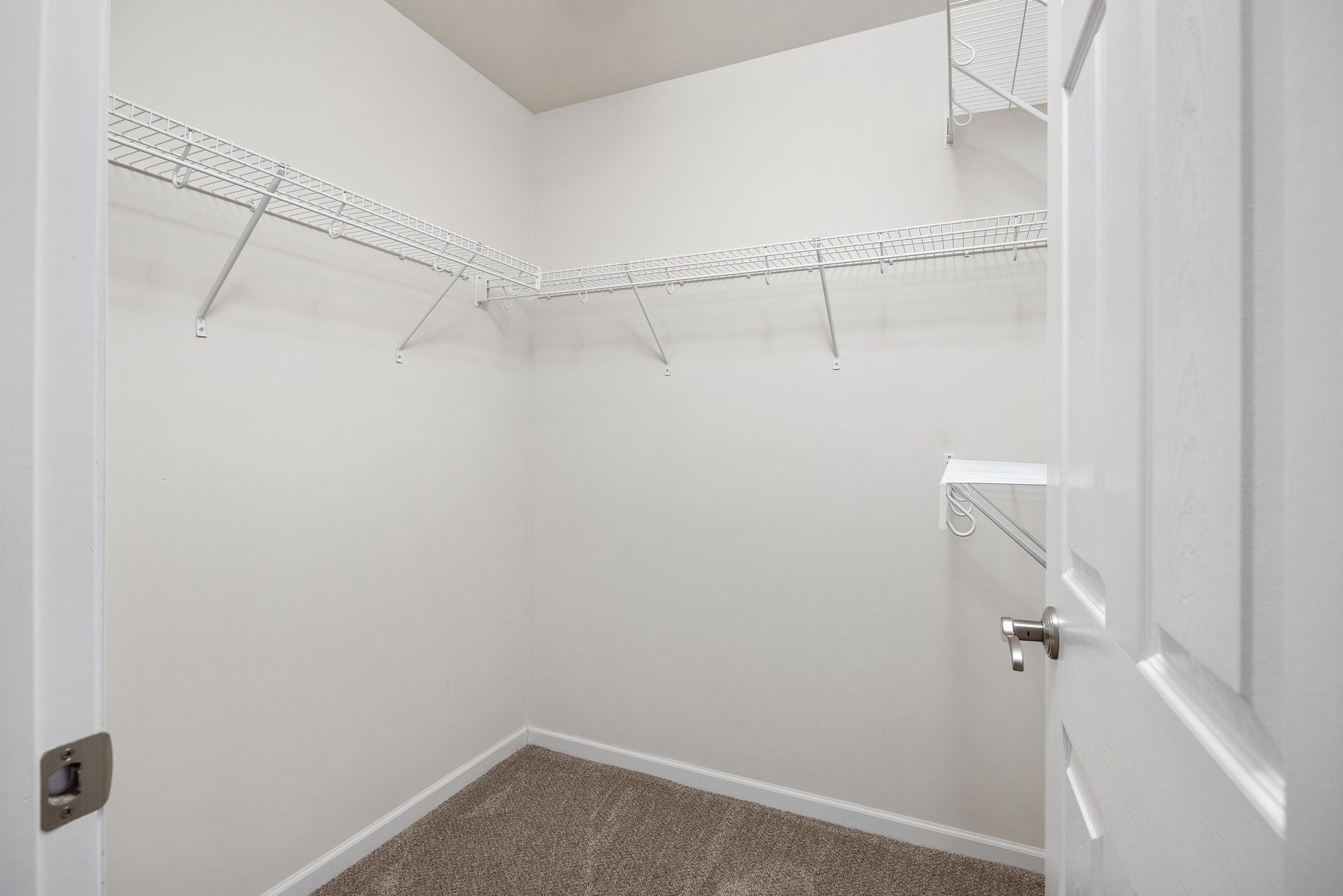 An empty walk in closet in a house with a door open.