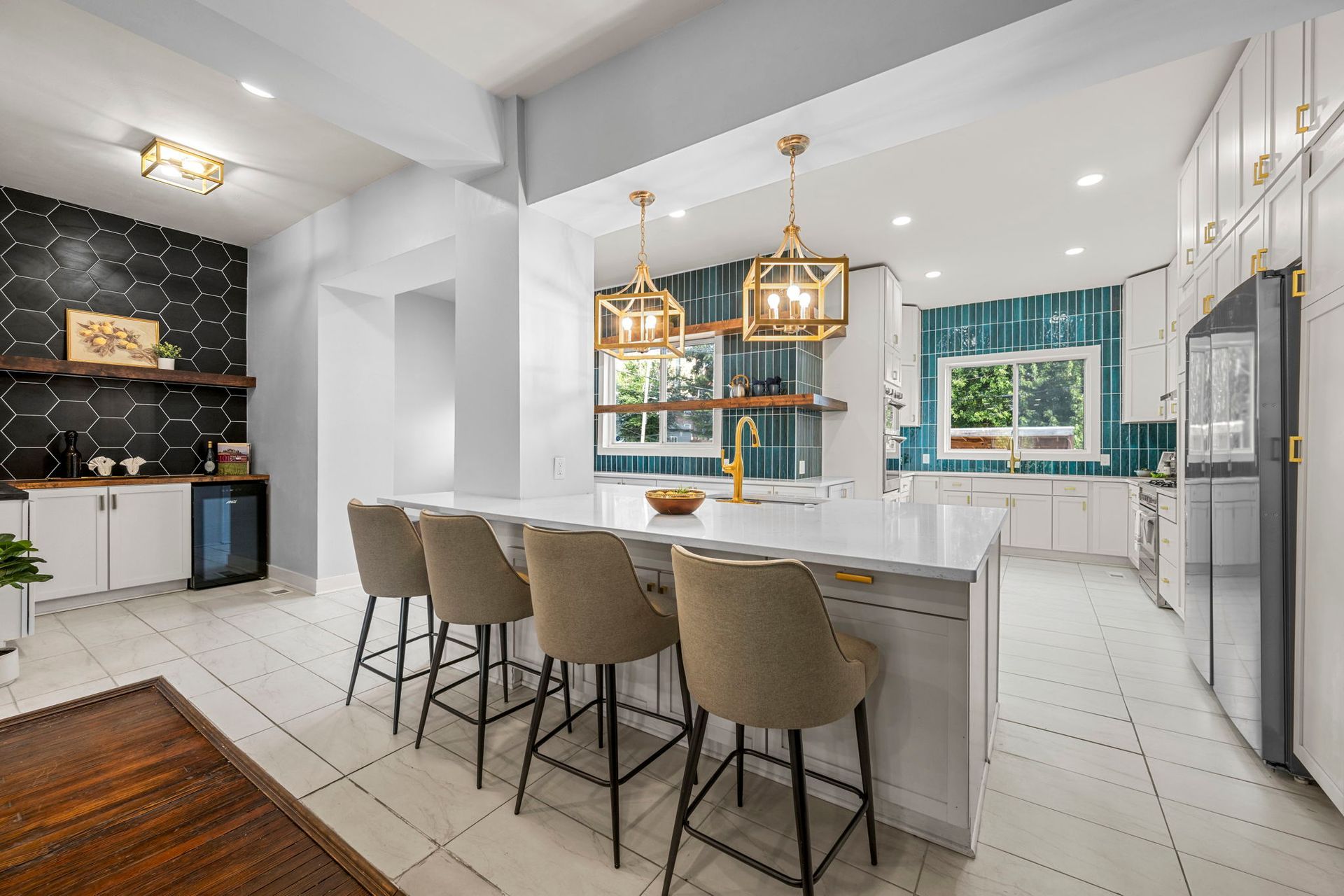 Modern kitchen with a large island, white cabinets, and teal tile backsplash.