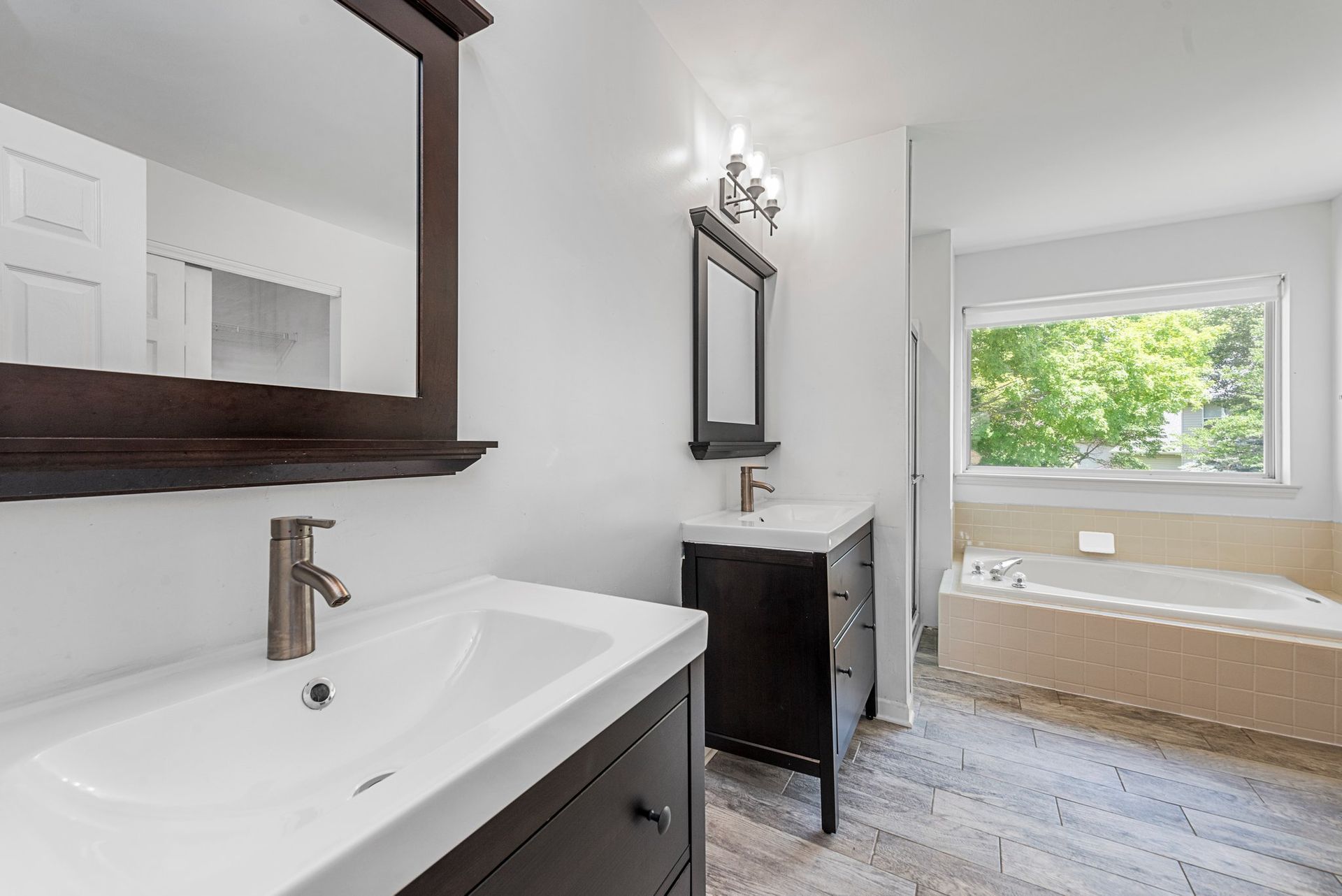 A bathroom with two sinks , a mirror and a tub.
