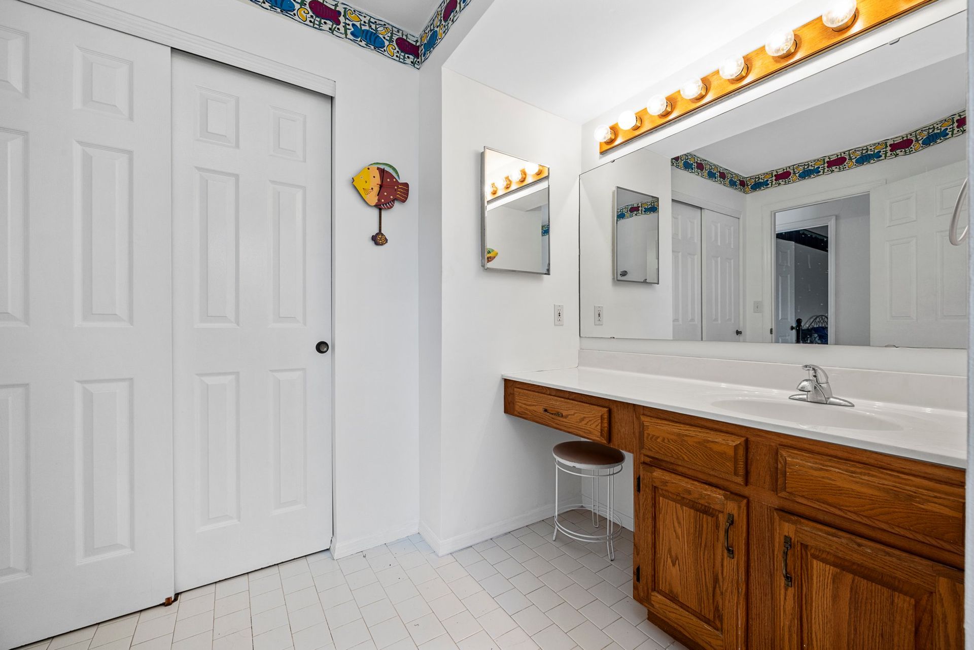 A bathroom with two sinks , a mirror and a stool.