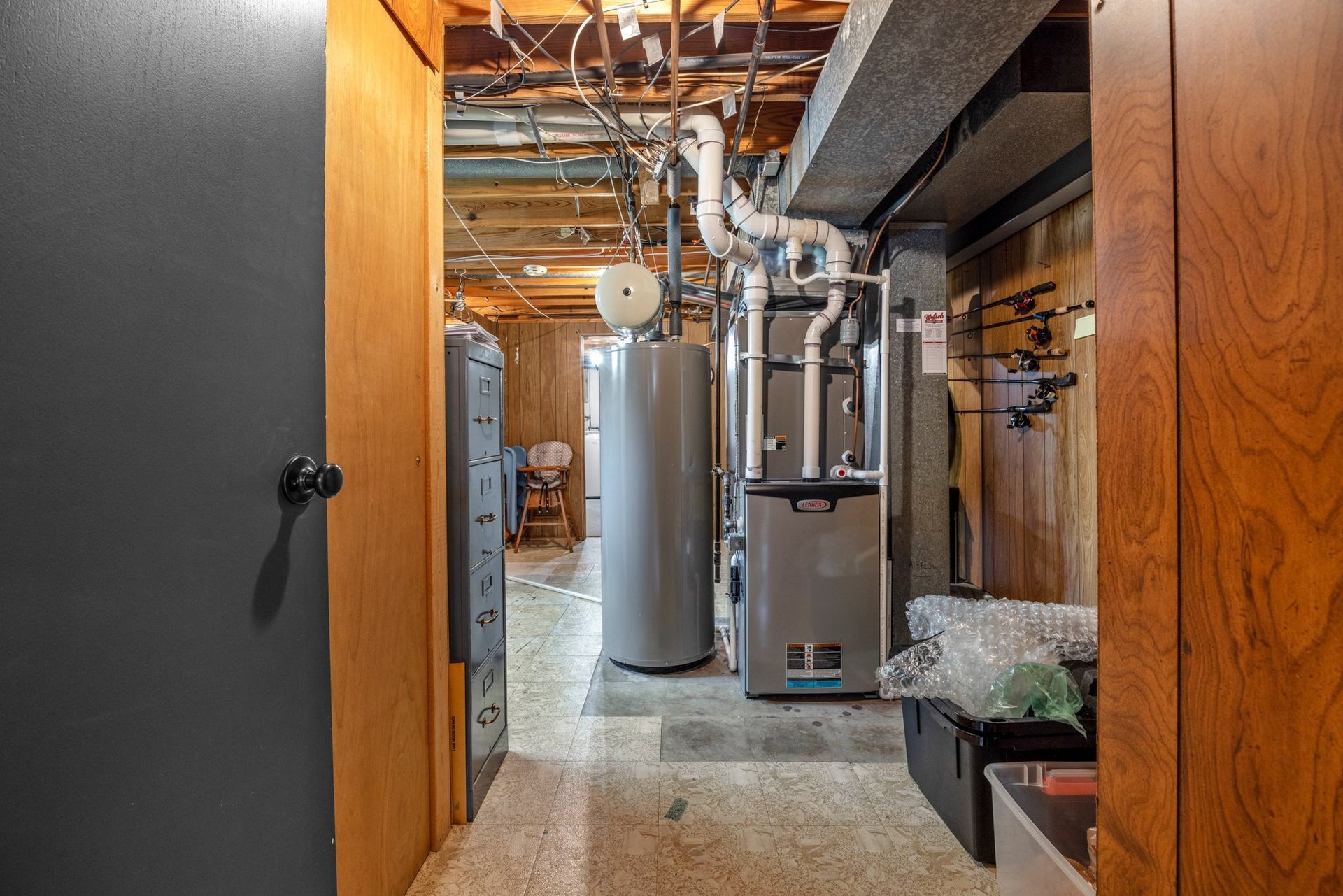 A hallway in a basement with a water heater and a furnace.