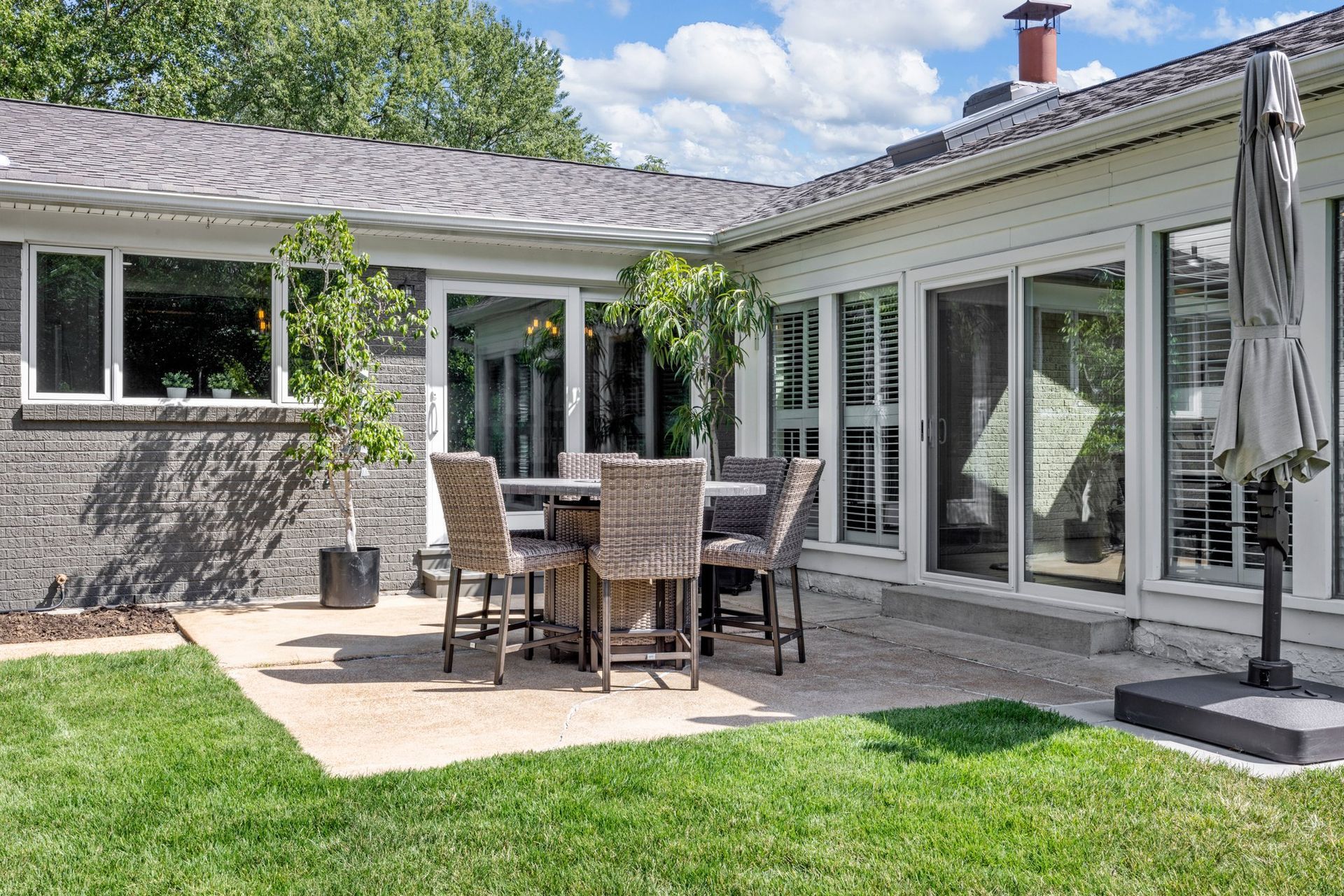 There is a patio with a table and chairs in the backyard of a house.