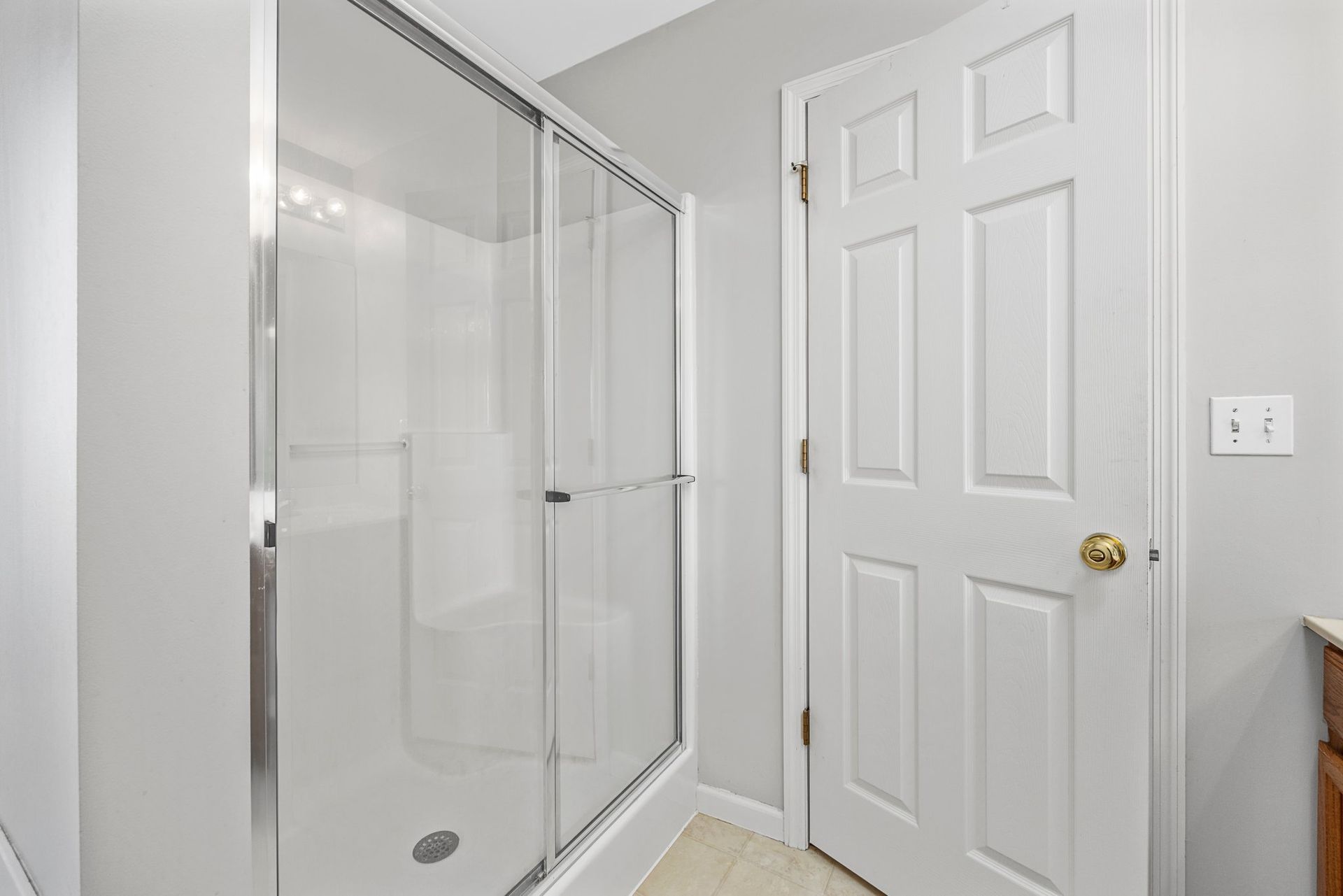 A bathroom with a walk in shower and a white door.