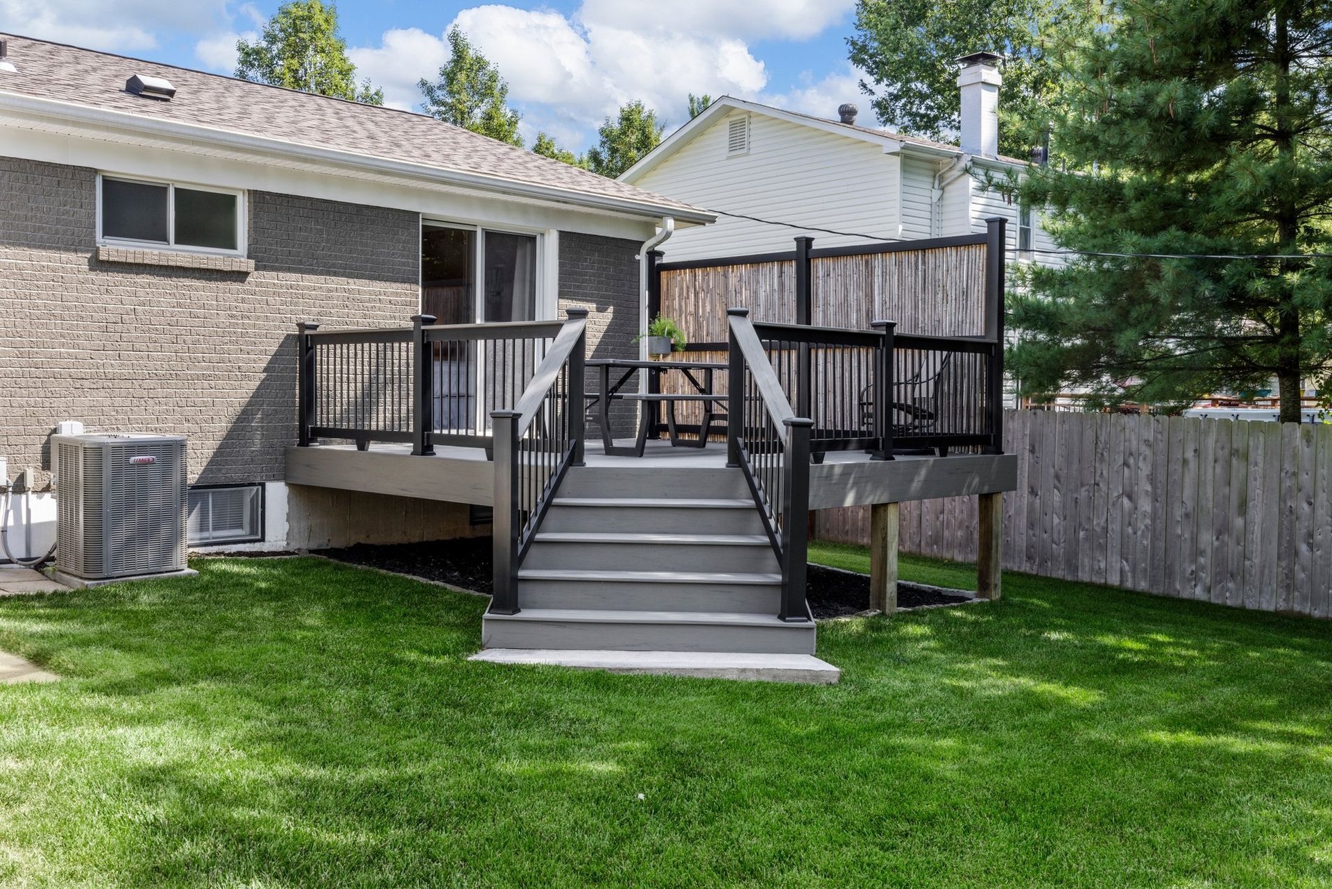There is a deck with stairs leading up to it in the backyard of a house.