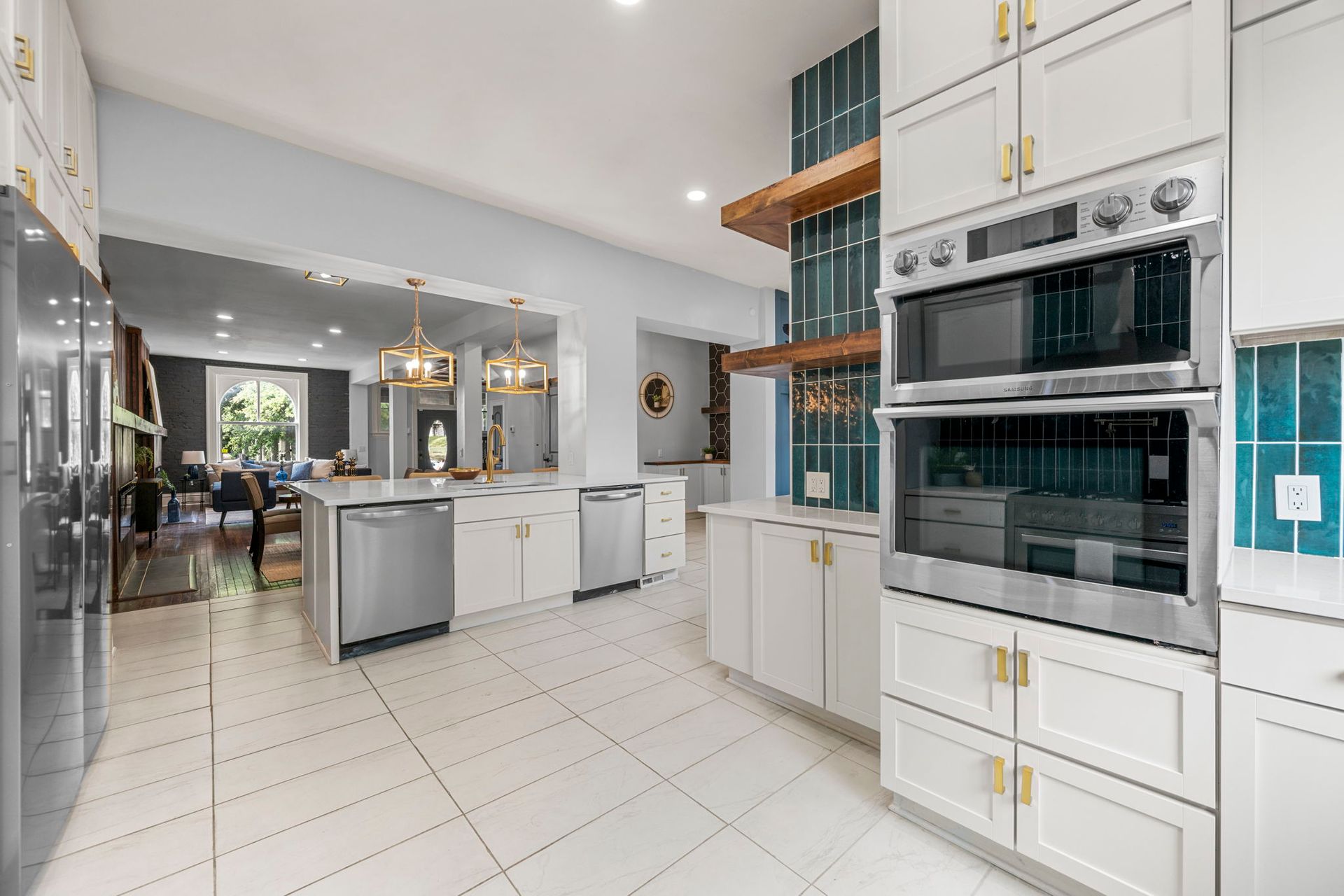 Bright white kitchen with stainless steel appliances, teal accents, and a view into a dining area.