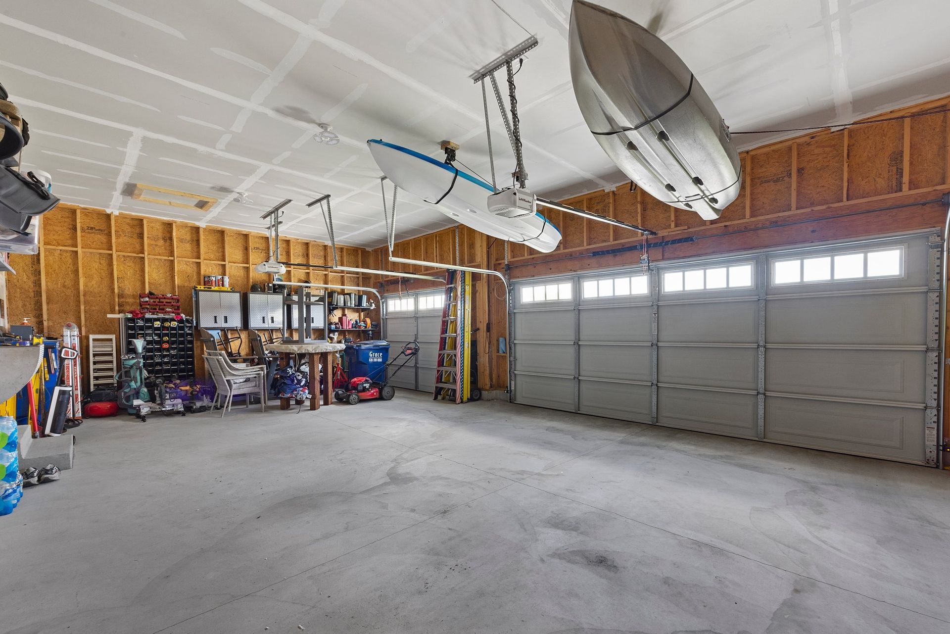 A large empty garage with two kayaks hanging from the ceiling.