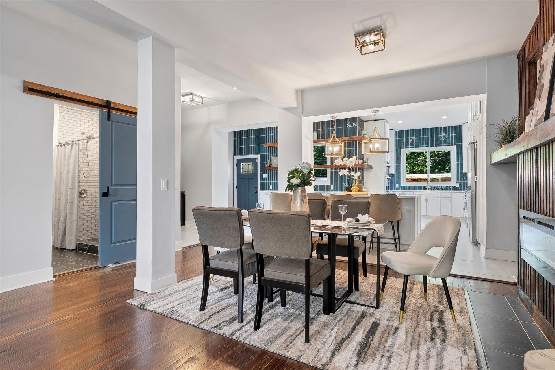 Dining room with table, chairs, open kitchen, blue accents, wood floors, and sliding barn door.
