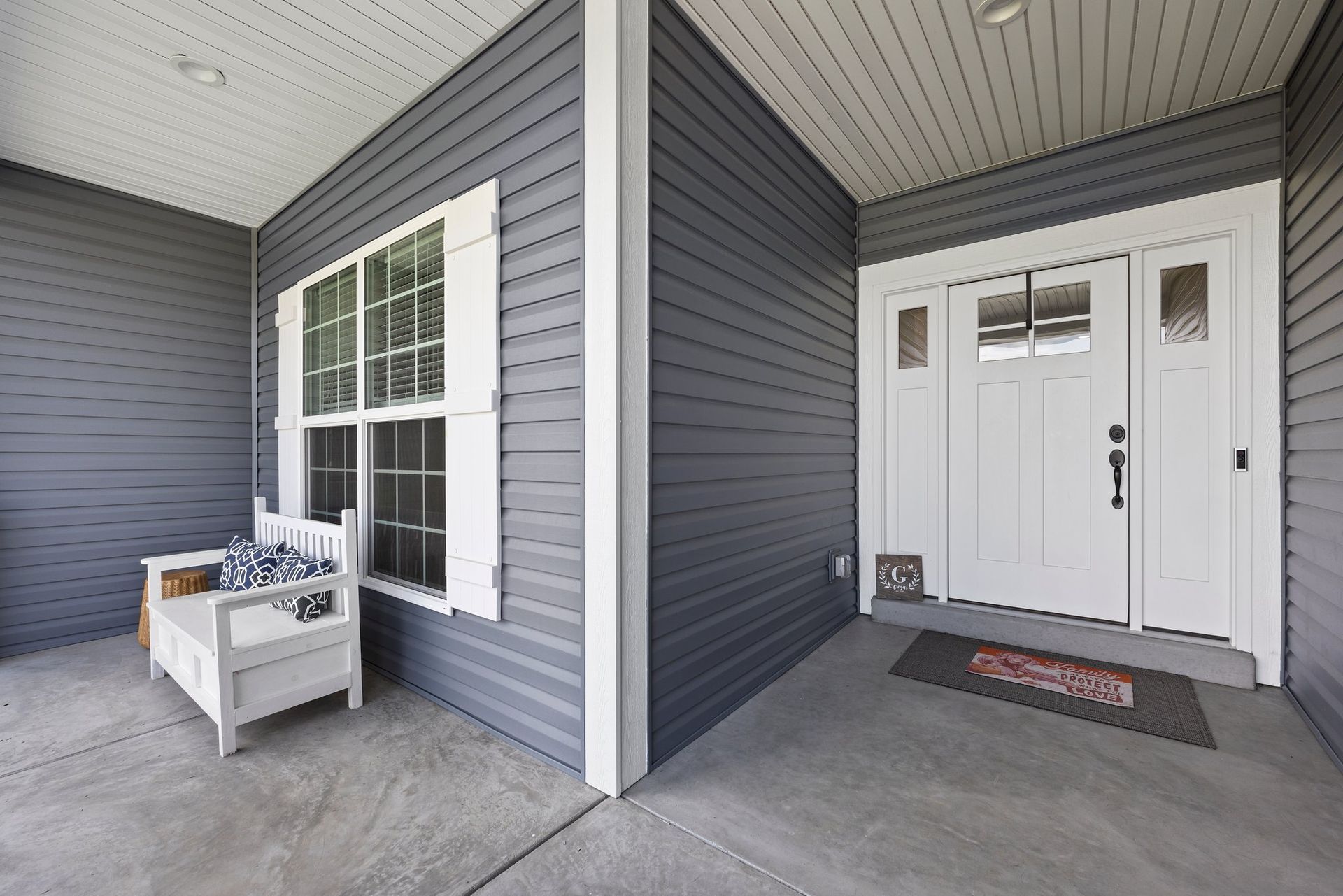 A porch with a white bench and a white door