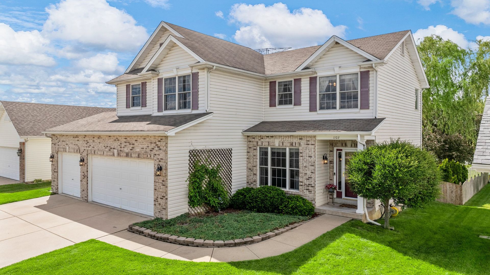 A large white house with two garages and a lush green yard.