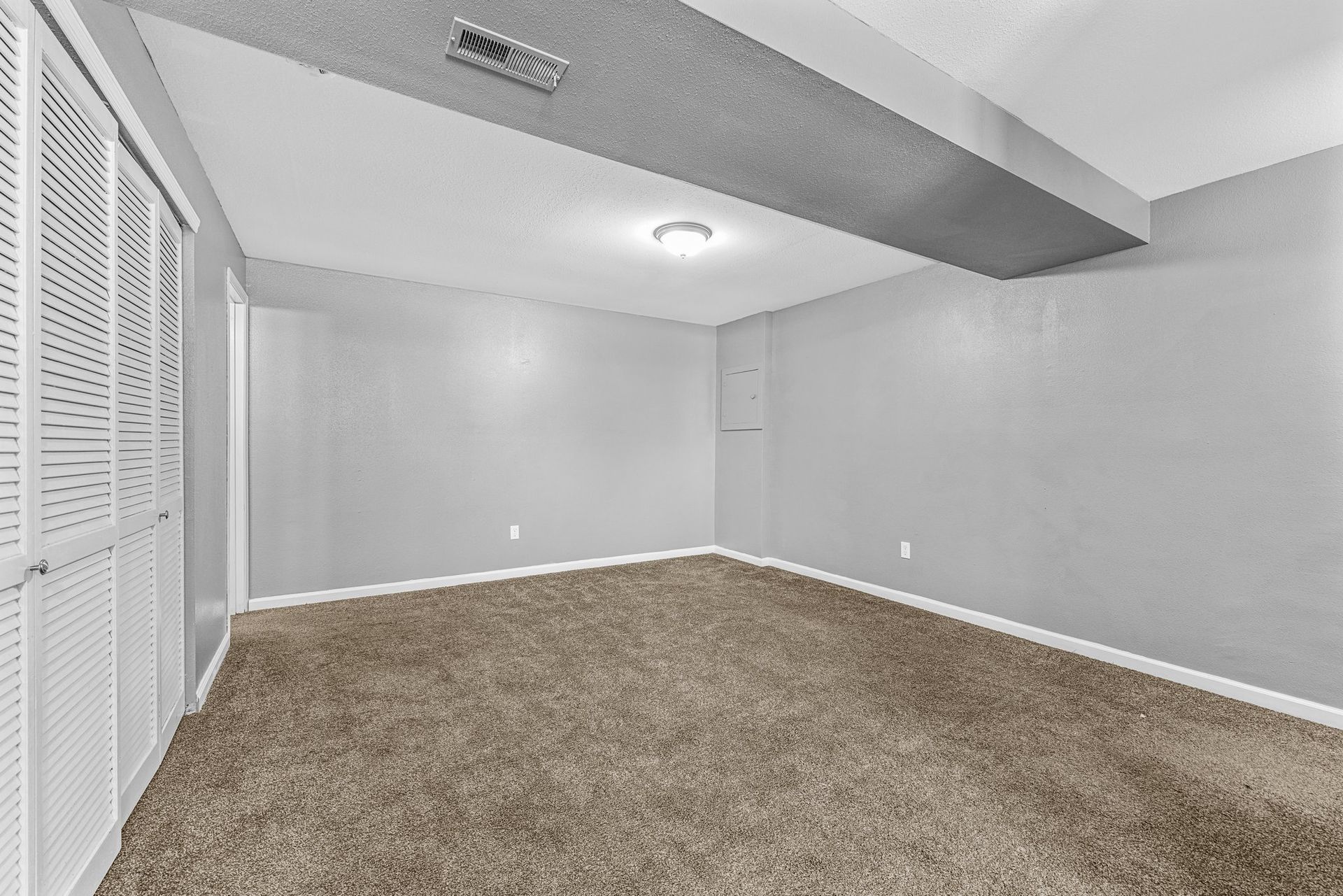 An empty room with a carpeted floor and white walls.