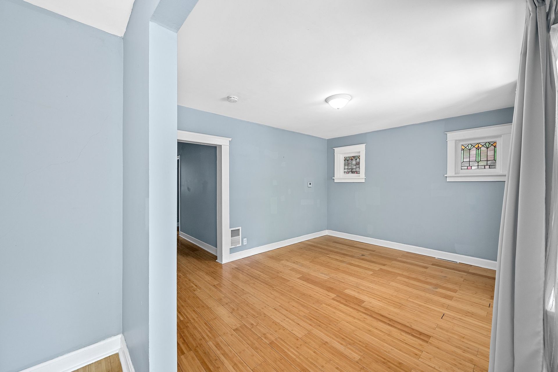 An empty living room with hardwood floors and blue walls.