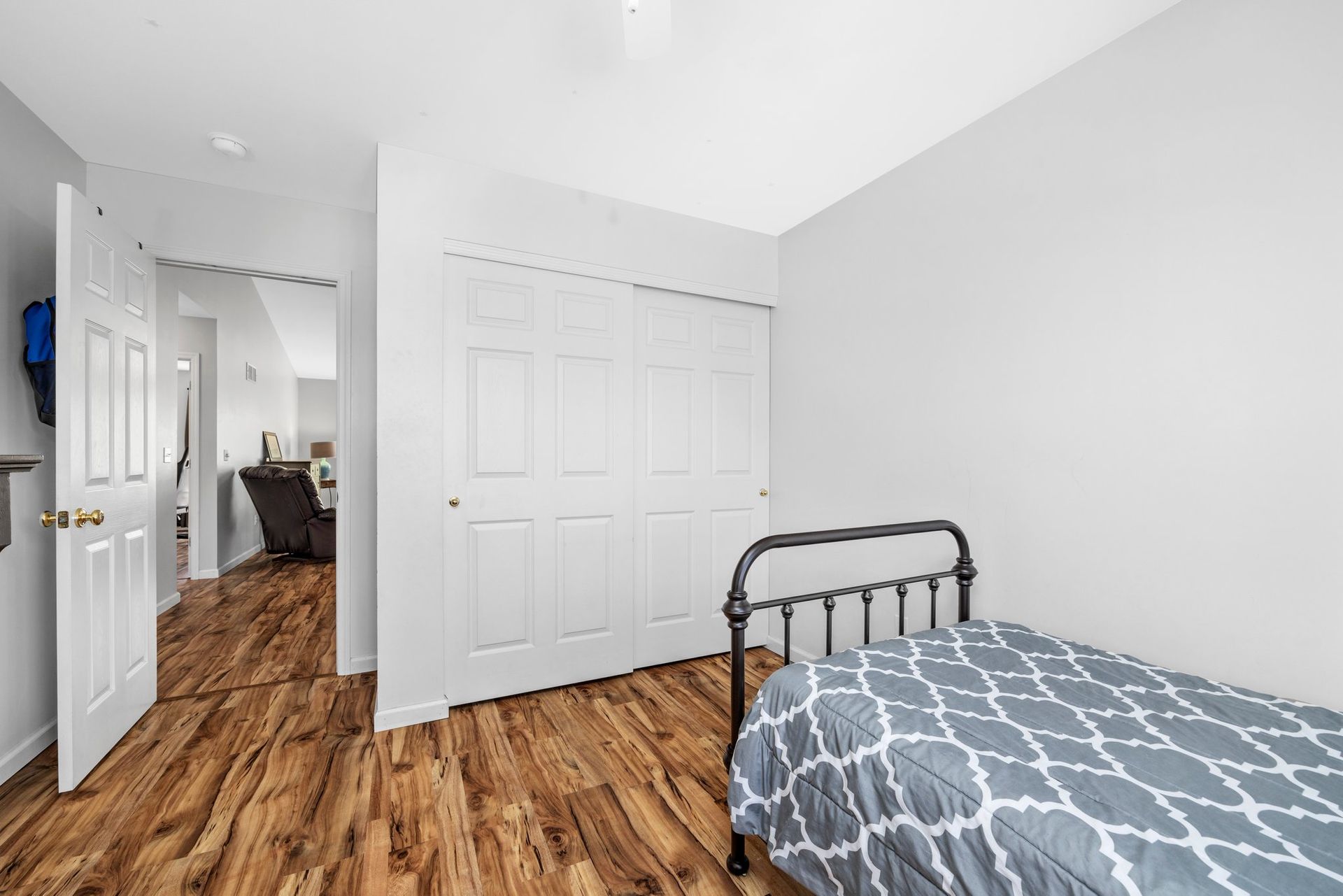 A bedroom with a bed , closets and hardwood floors.