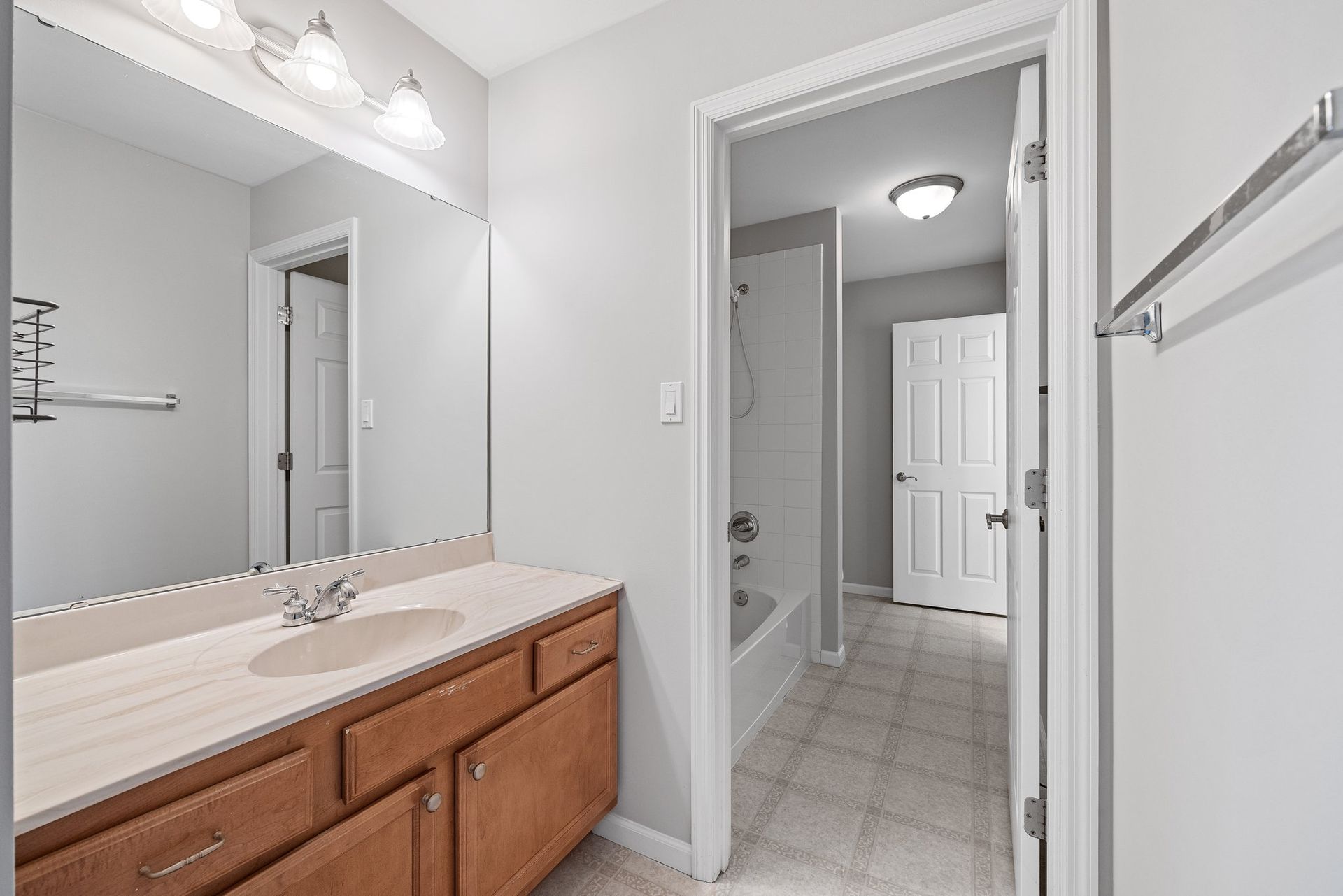 A bathroom with a sink , mirror , and towel rack.