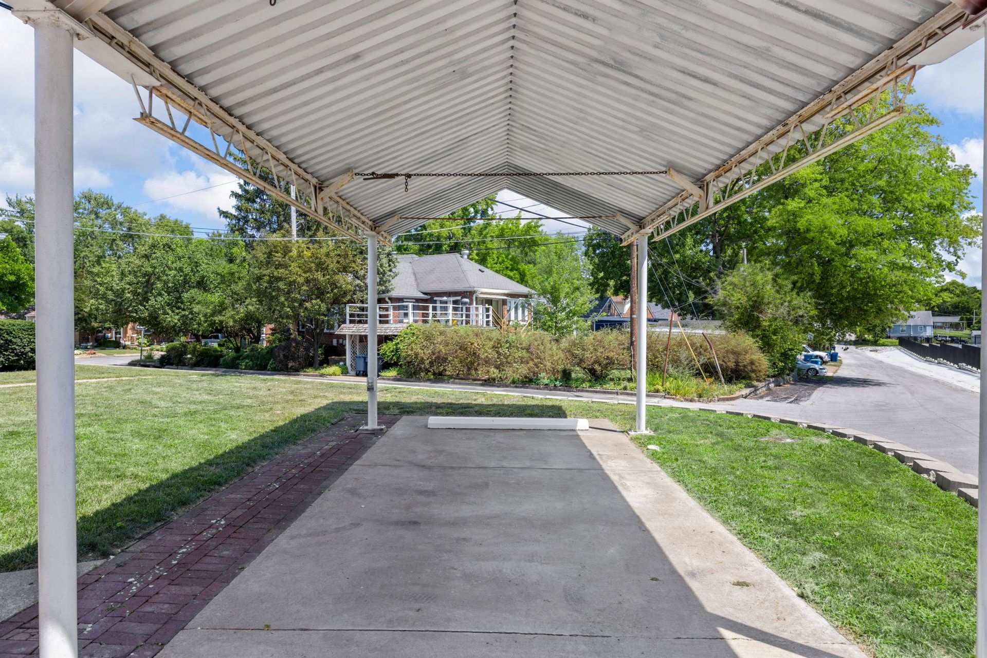 A parking lot with a covered walkway leading to a house.
