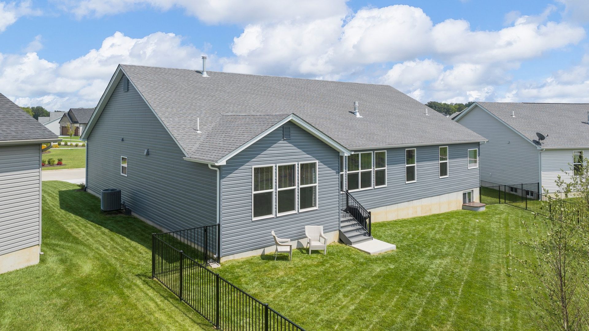 The back of a house with a fence in front of it.