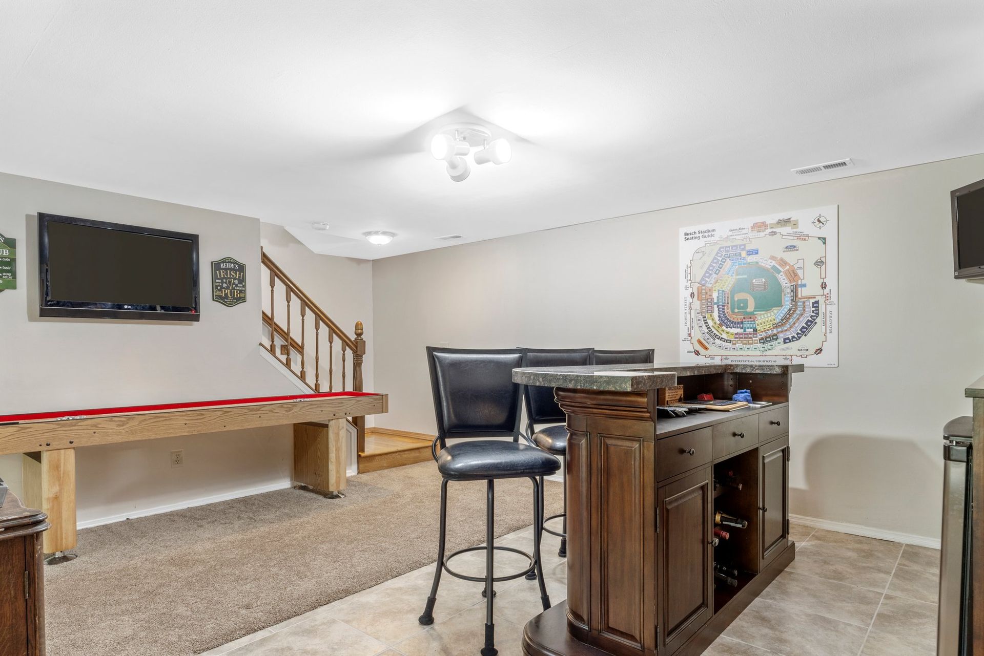 A basement with a pool table and a bar.