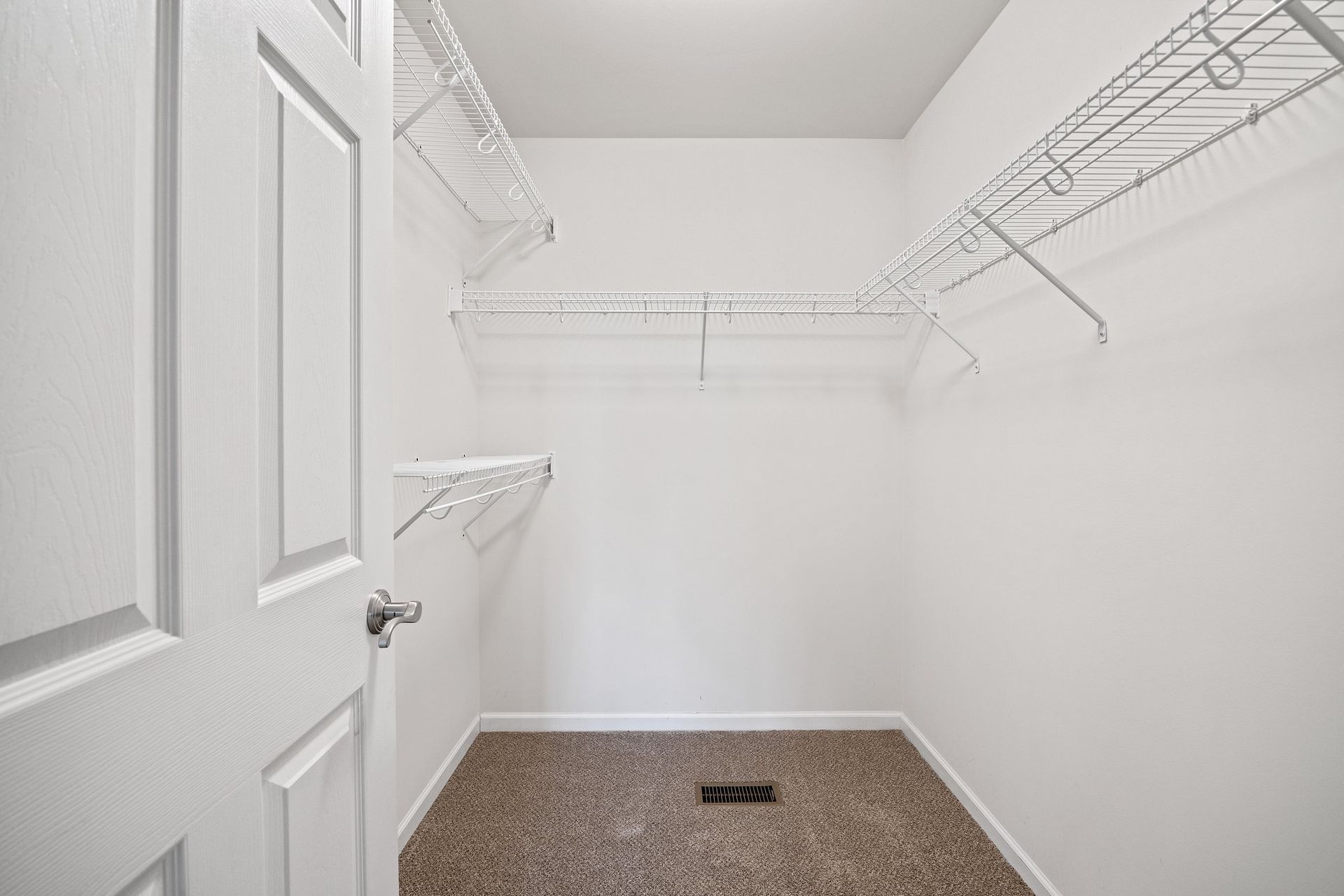 An empty walk in closet with shelves and a door.