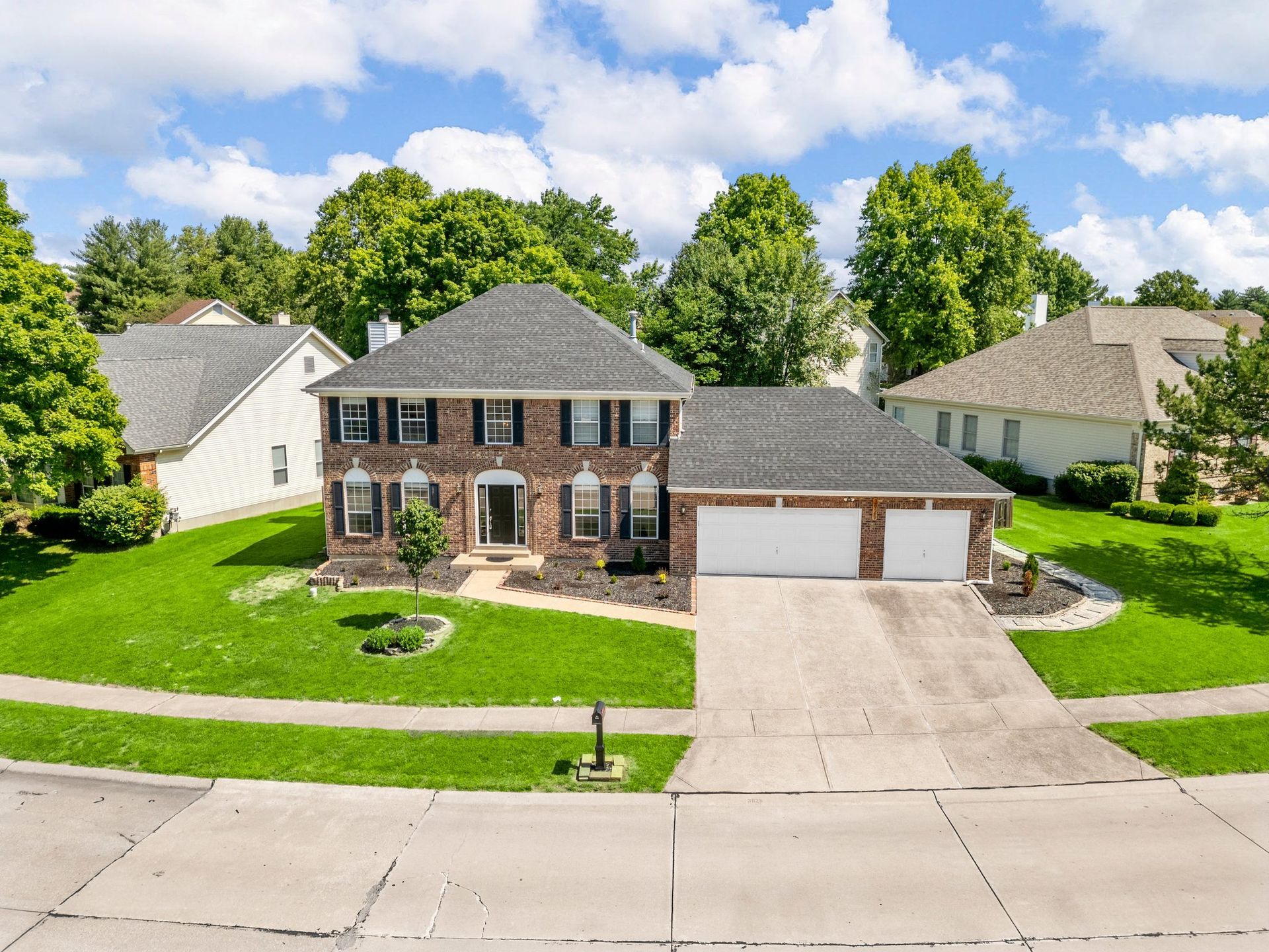 An aerial view of a brick house with a large driveway