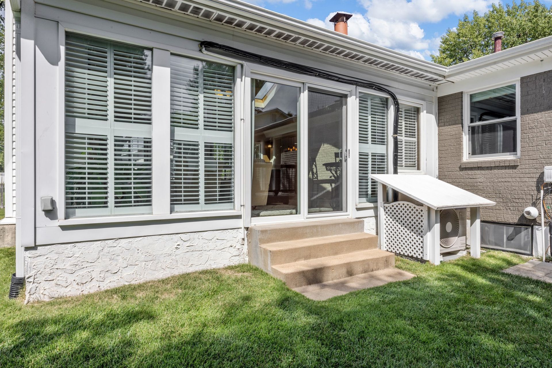 The back of a house with a sunroom and stairs leading to it.