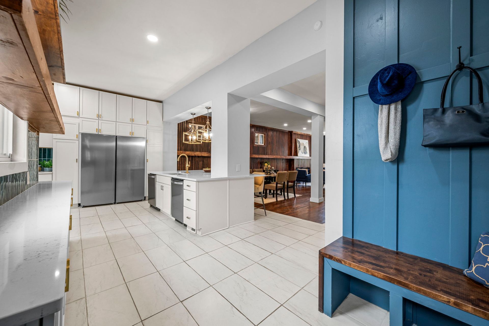 A modern kitchen and entryway with blue accents and wood bench.