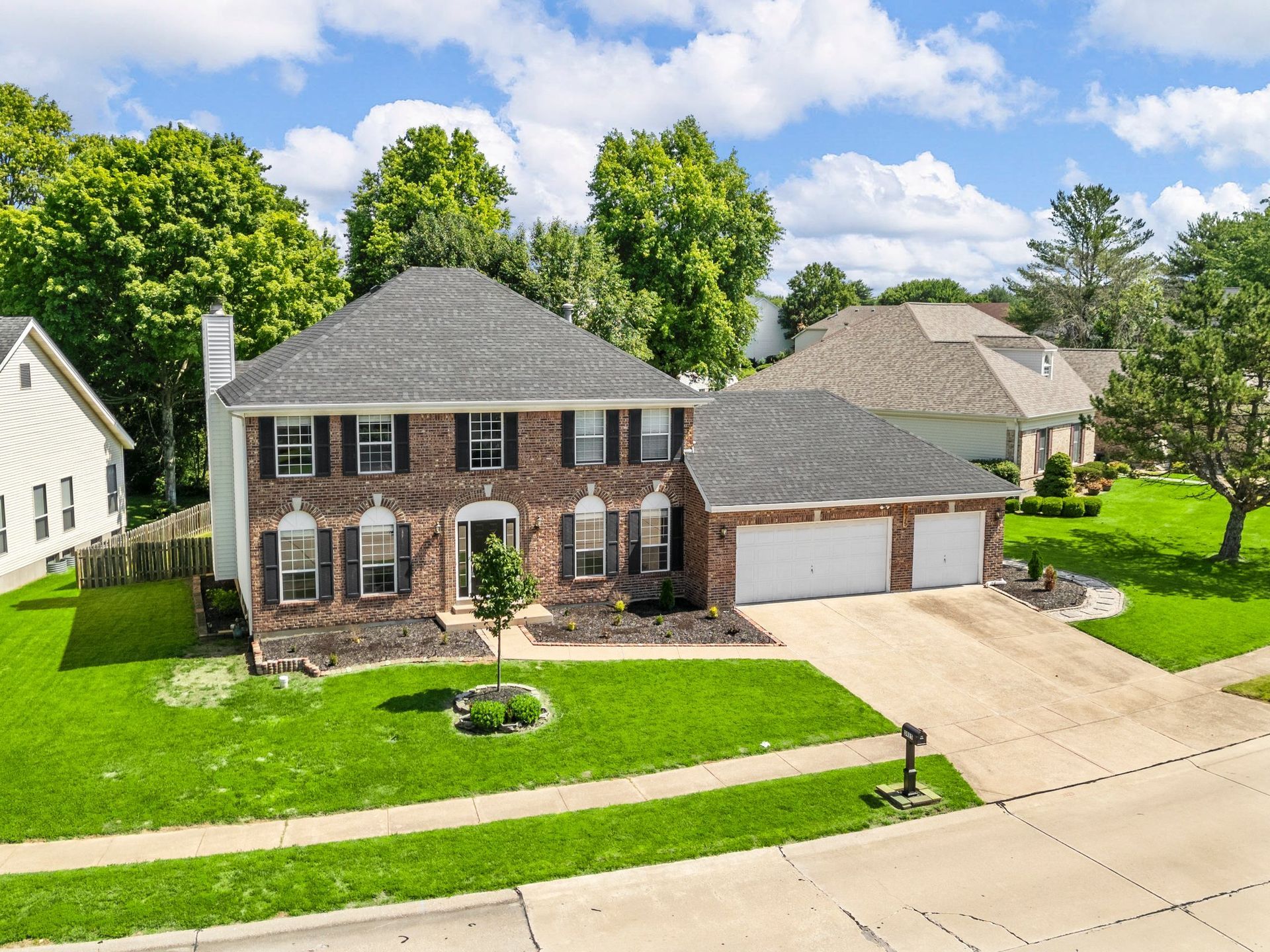 An aerial view of a large brick house with two garages