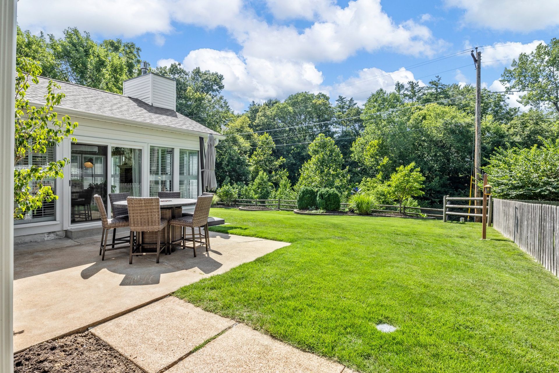 There is a patio with a table and chairs in the backyard of a house.
