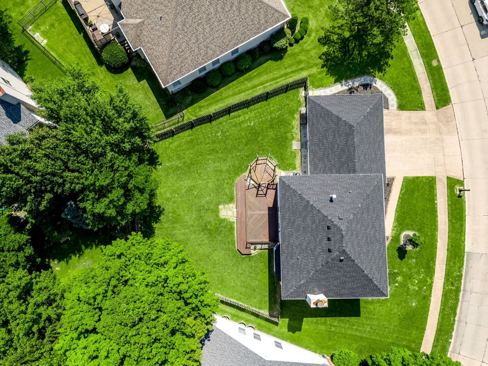 An aerial view of a house in a residential area surrounded by trees.