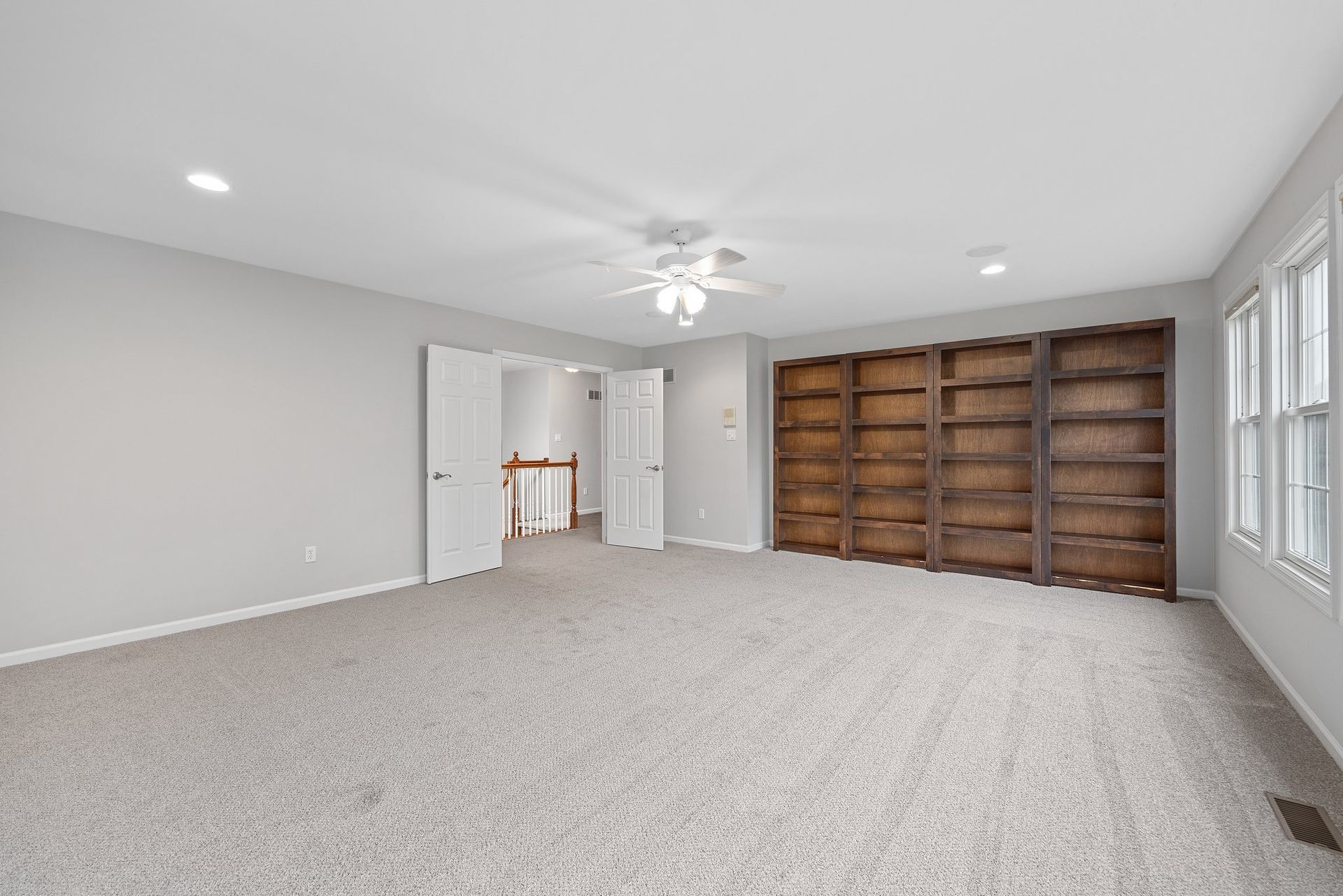A large empty room with a lot of shelves and a ceiling fan.