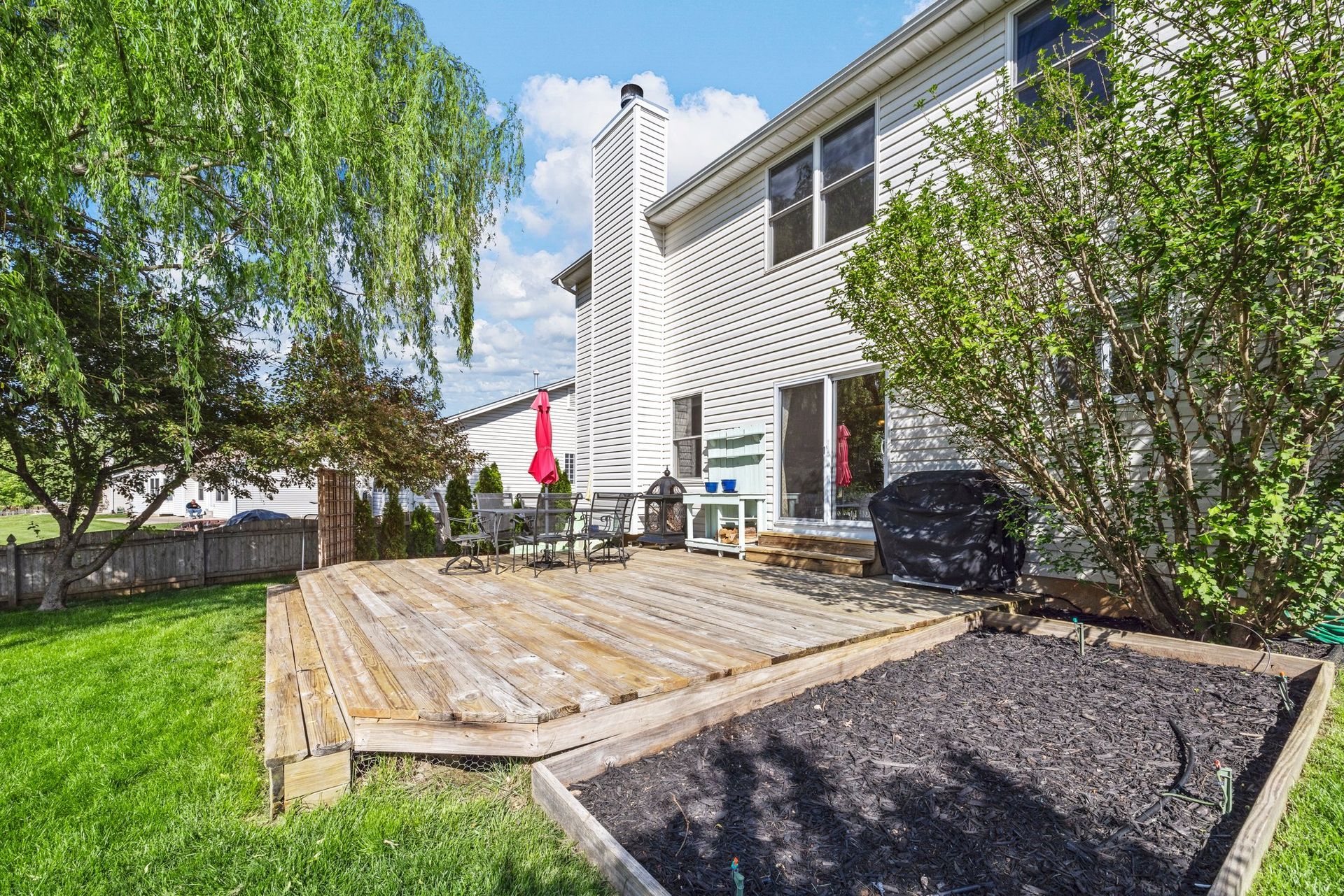 There is a large wooden deck in the backyard of a house.