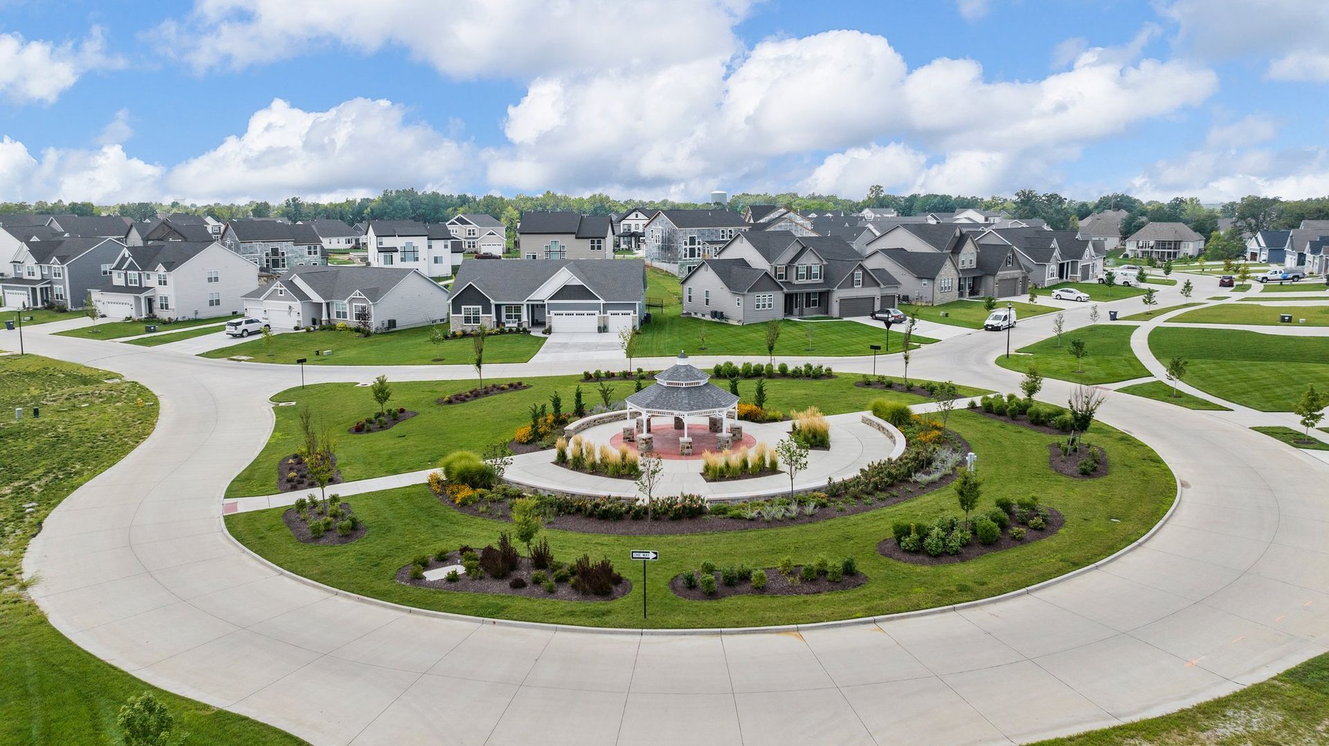 An aerial view of a residential neighborhood with a circular driveway and a gazebo in the middle.