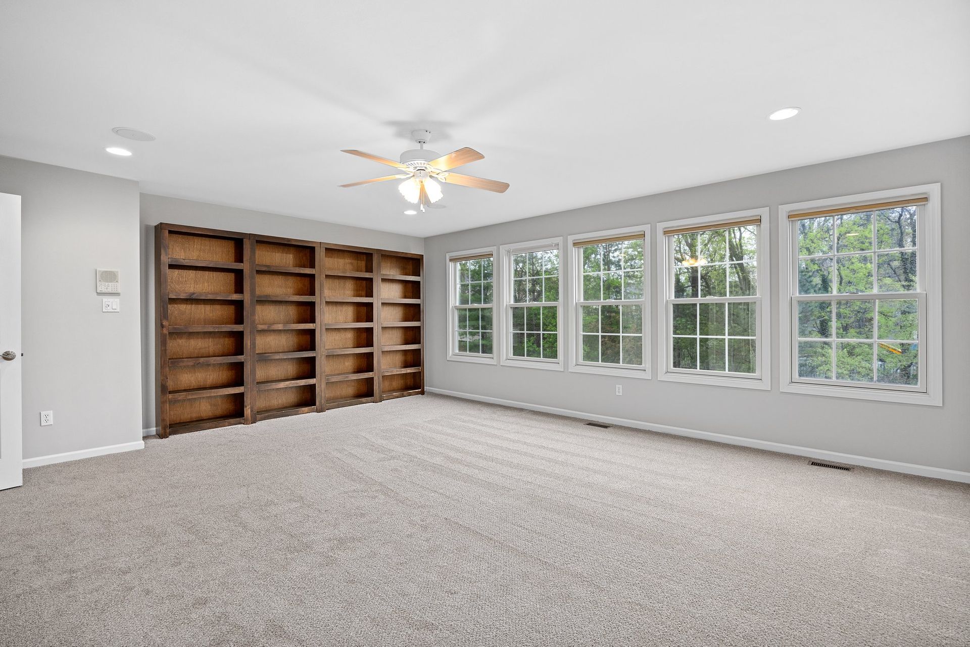 A large empty room with a lot of windows and shelves.