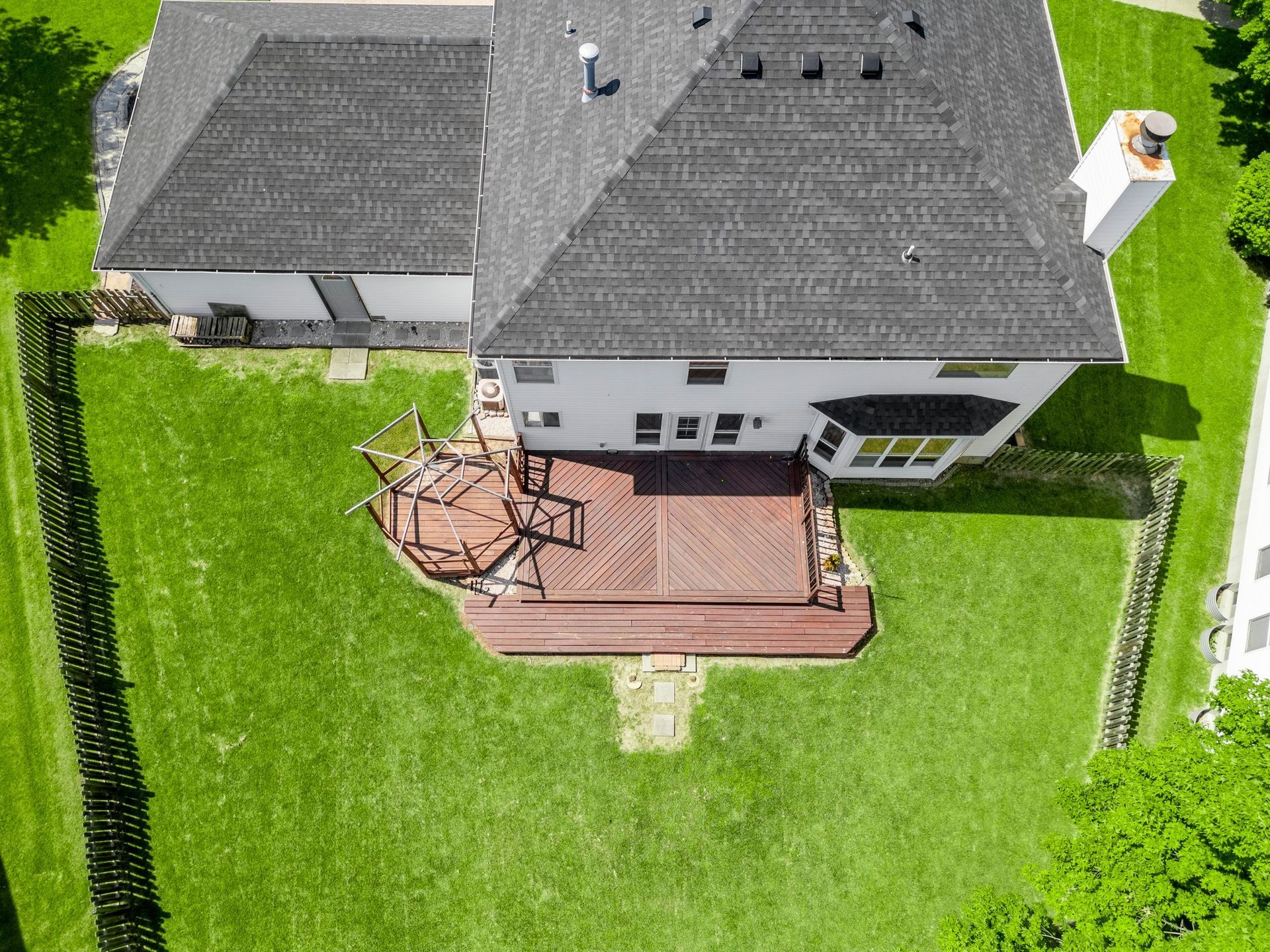 An aerial view of a house with a wooden deck in the backyard.