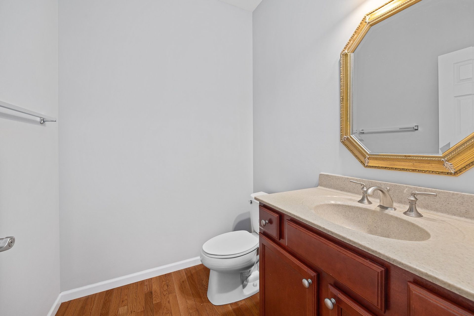 A bathroom with a toilet , sink and mirror.