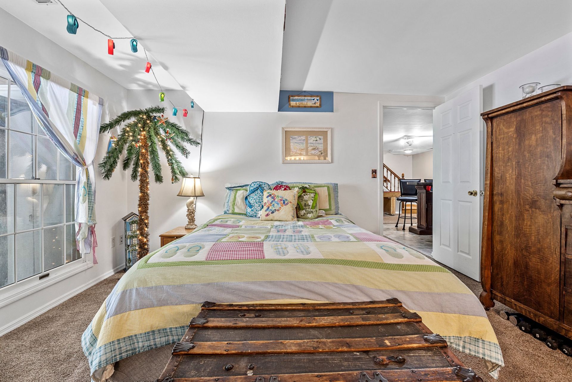 A bedroom with a king size bed , a wooden table and a palm tree.