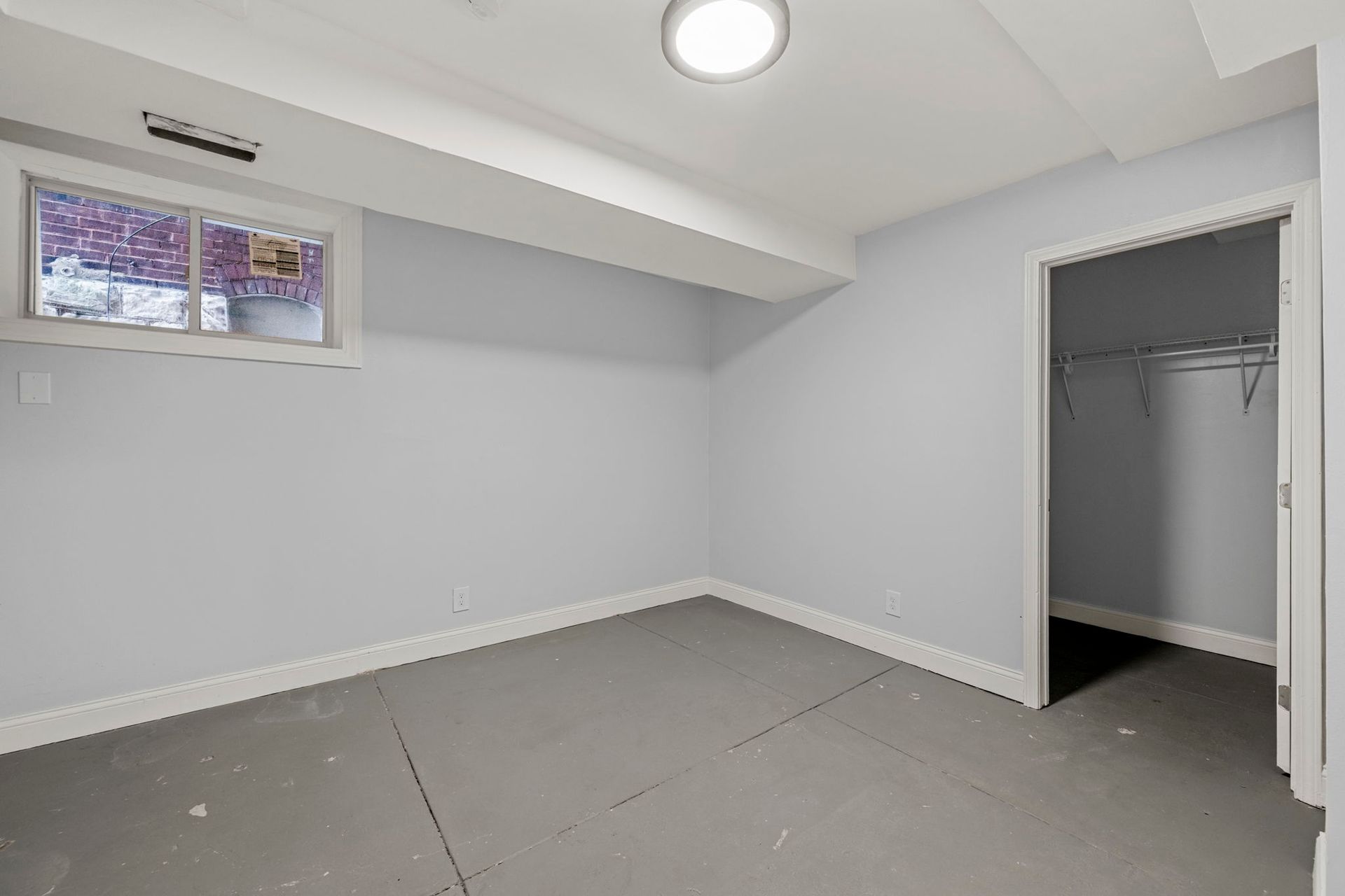 Empty gray room with a closet and small window.