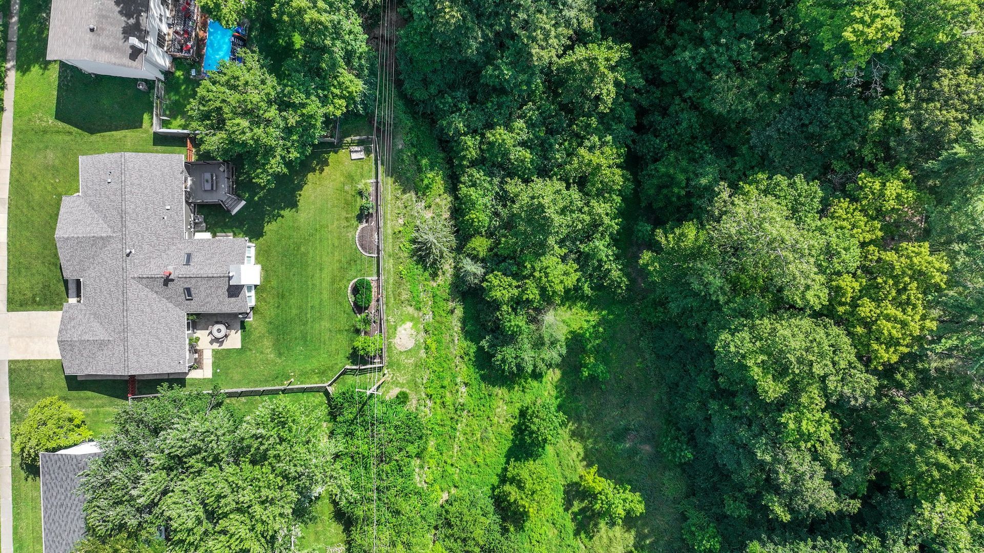 An aerial view of a house surrounded by trees and grass.