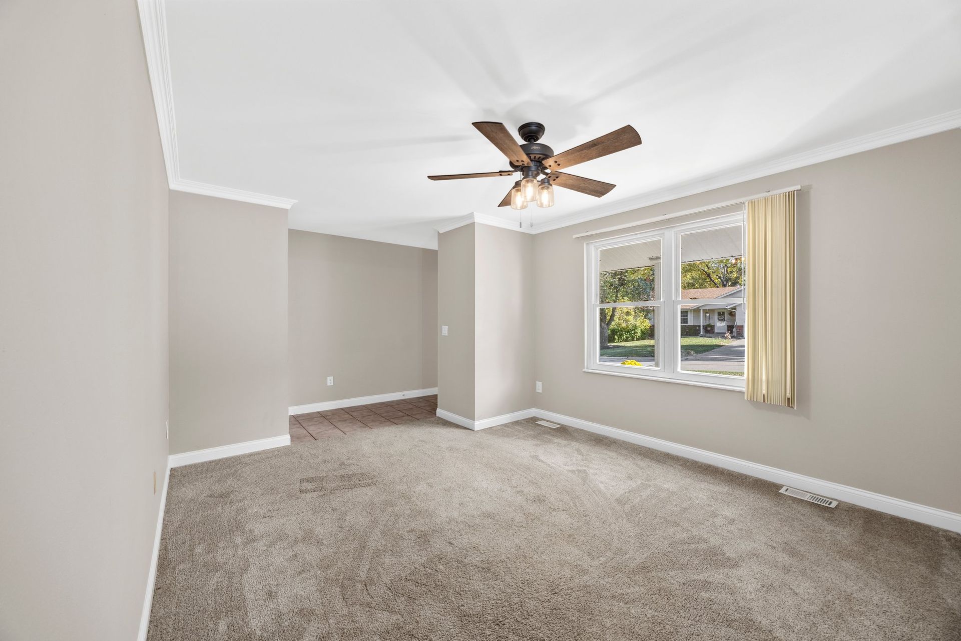 An empty bedroom with a ceiling fan and two windows.
