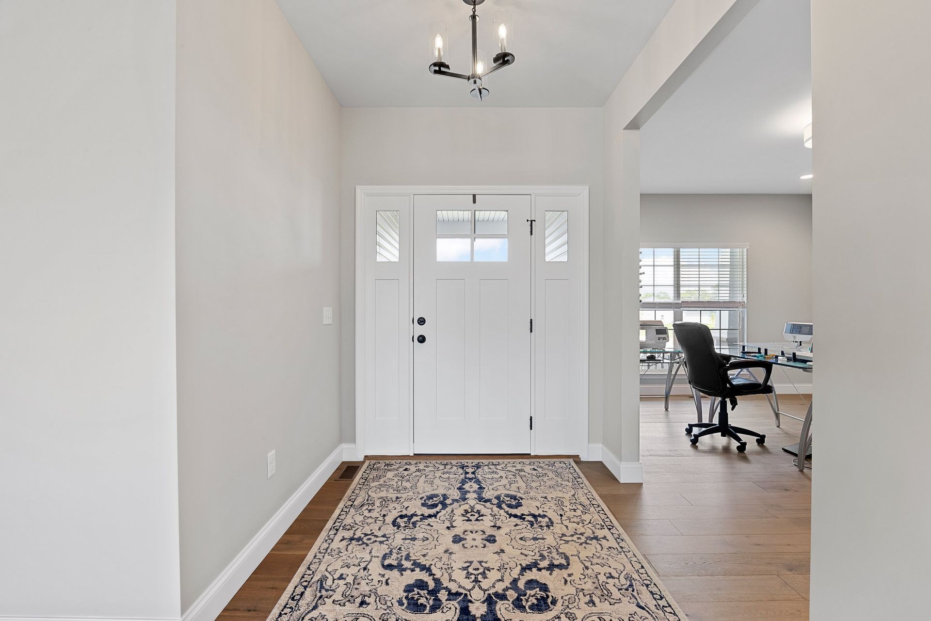 A hallway in a house with a rug and a desk.