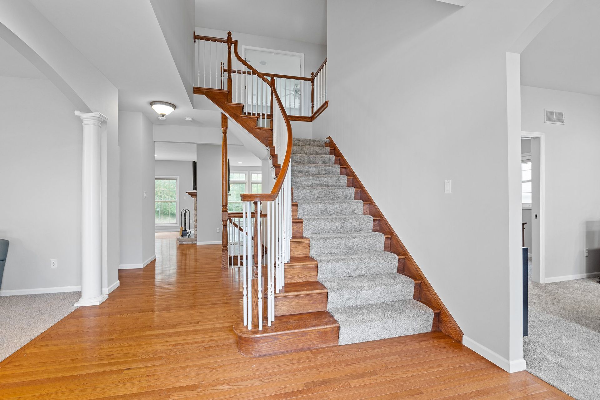 A staircase in a house with a wooden railing and carpeted steps leading up to the second floor.